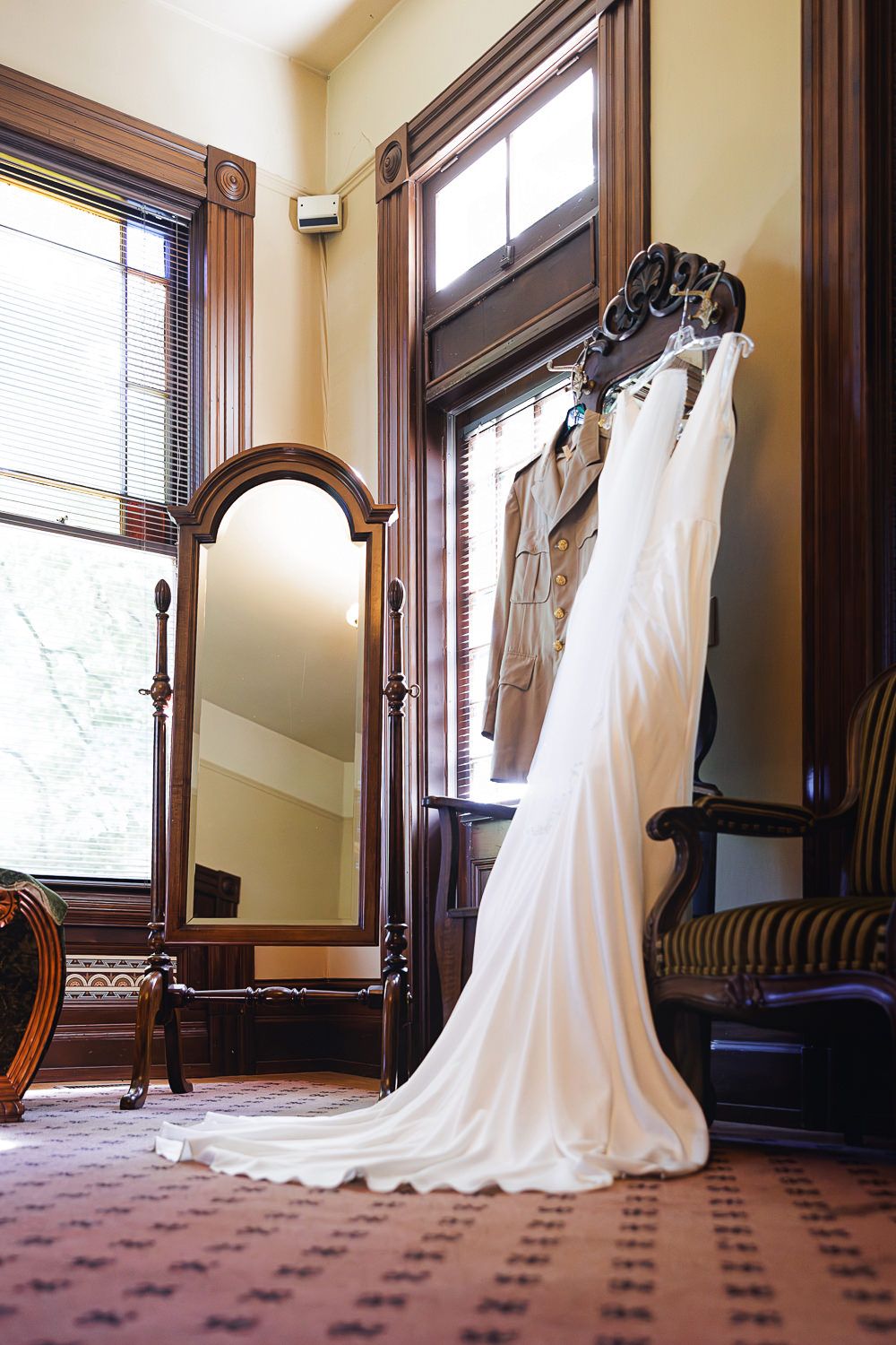 A sequence of wedding dresses displayed in an elegant room with ornate wooden trim and carpeted flooring.