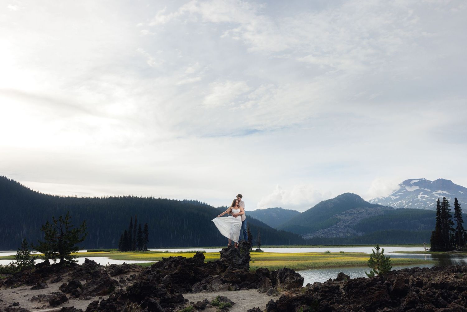 A scenic coastal view of Oregon's Sparks Lake with mountains in the background and sandy shore in the foreground.