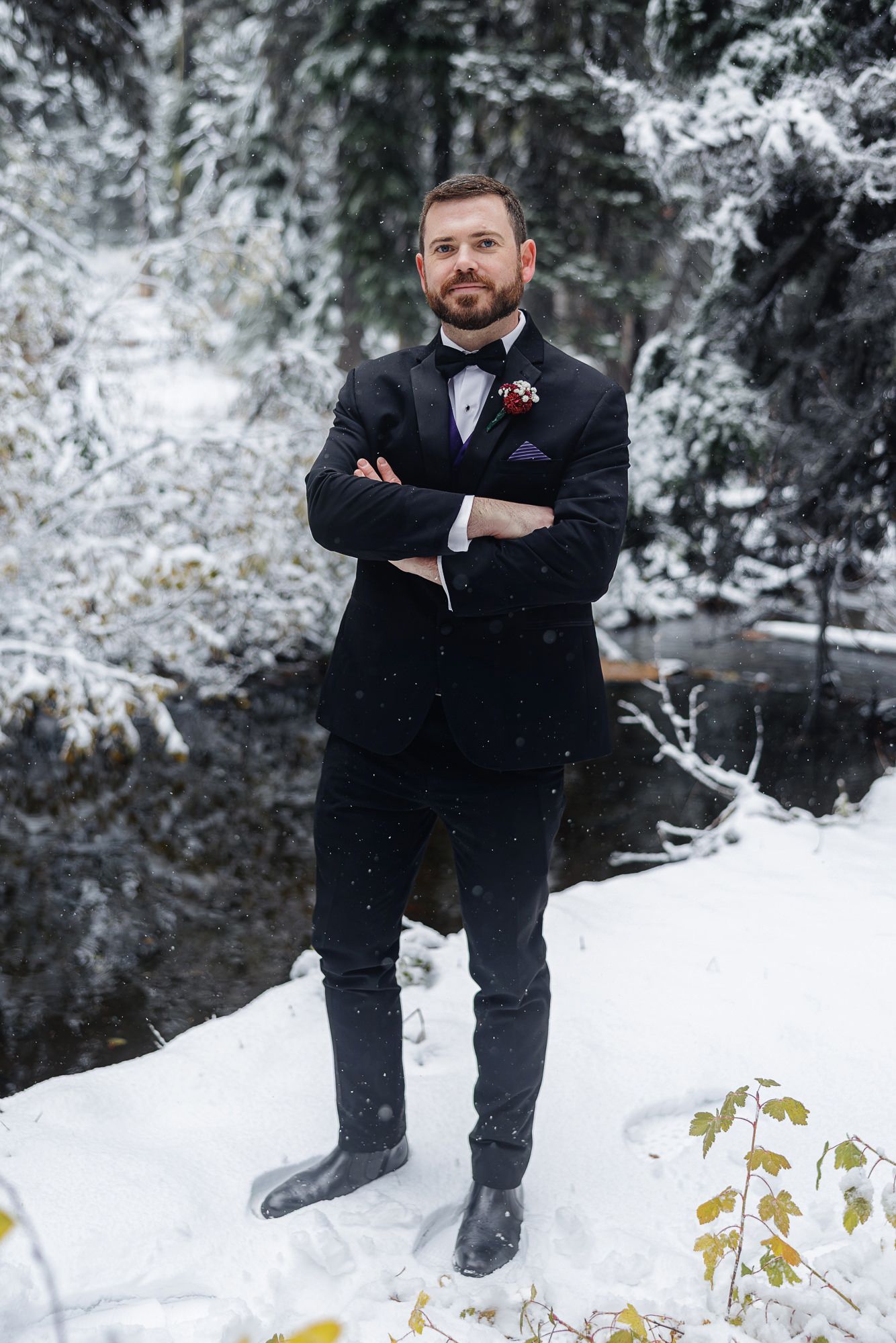 Winter portrait in a snowy forest setting with evergreen trees and a frozen creek in the background.