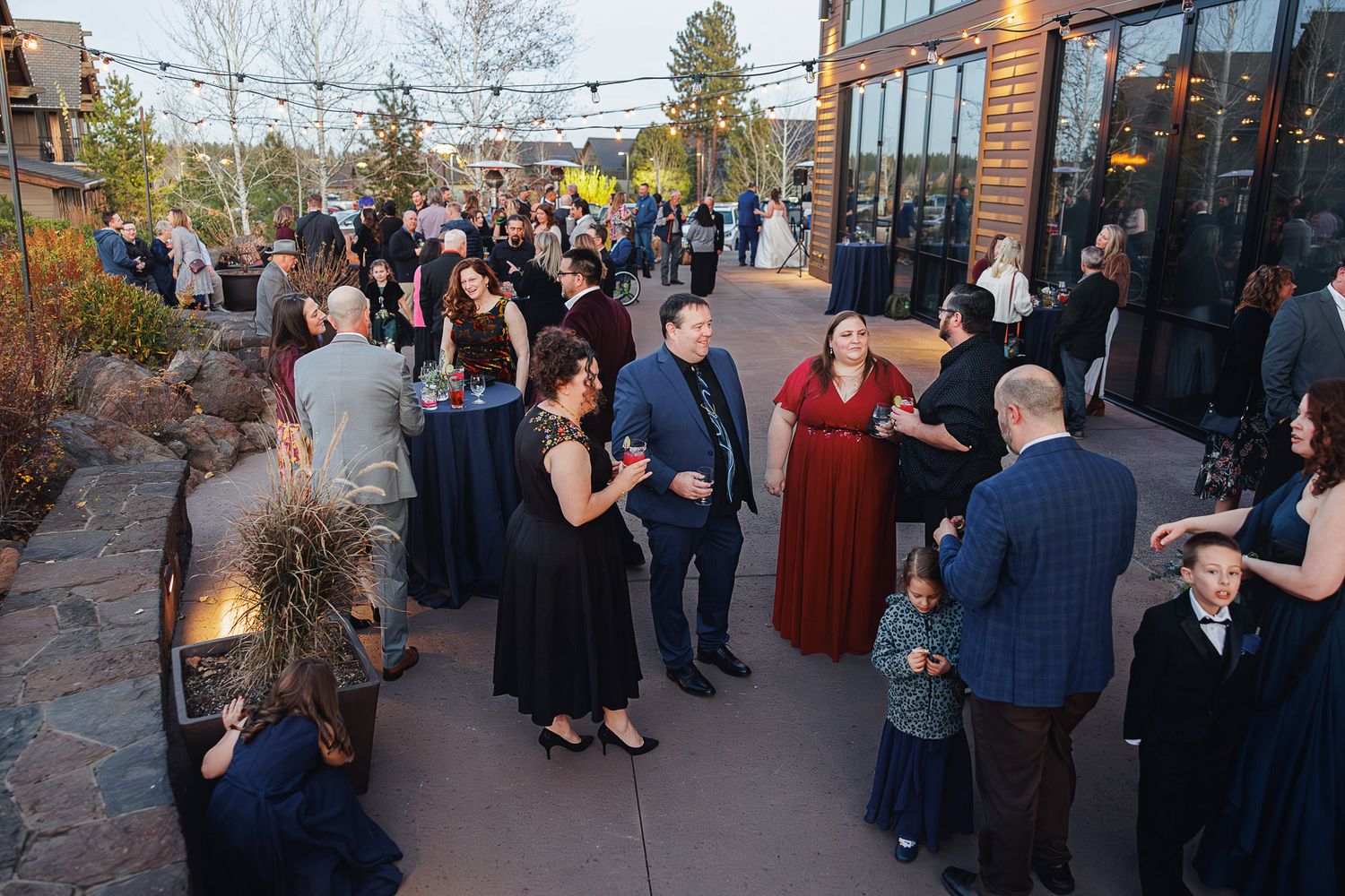A group of people gathered outside a building for a social event at dusk.