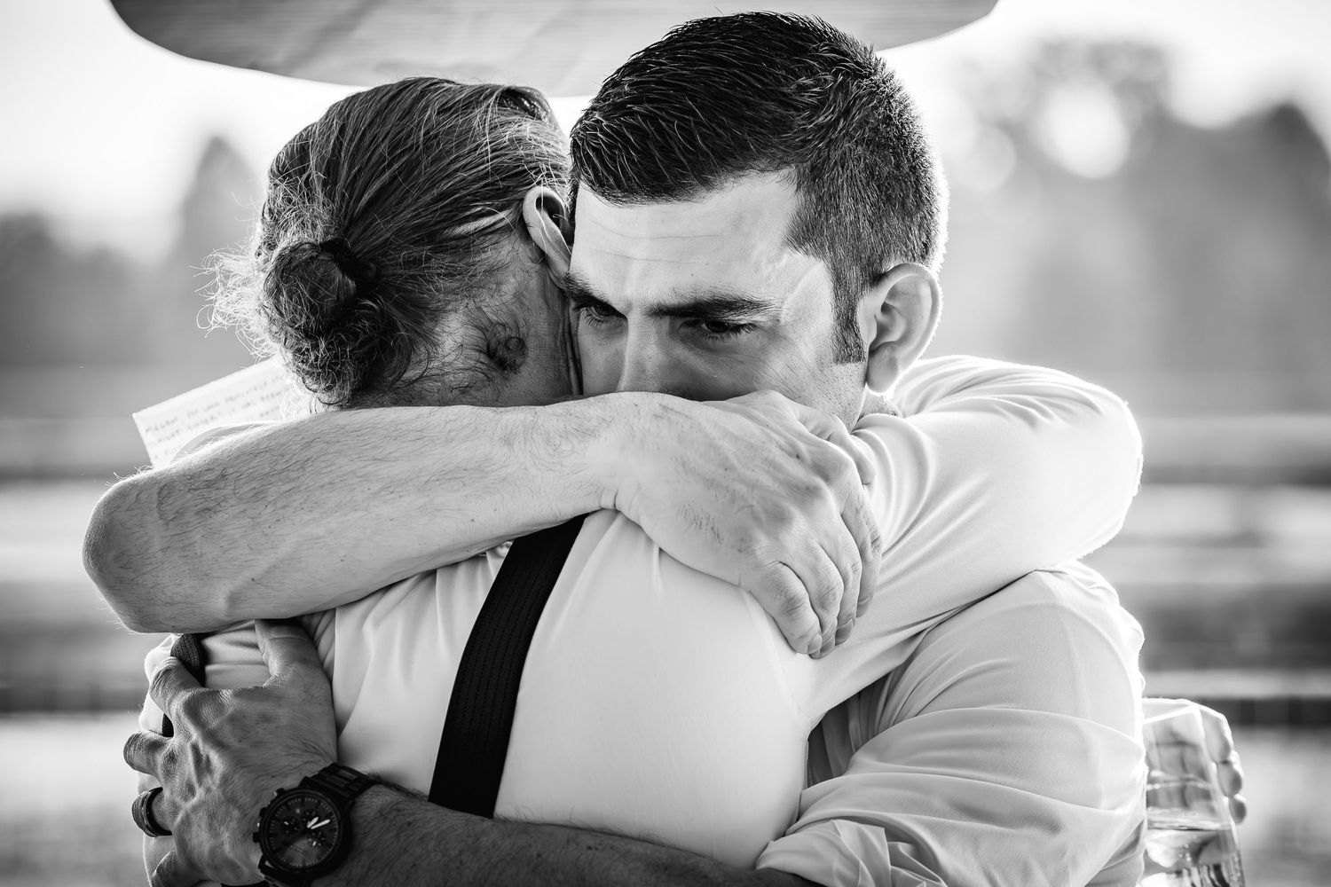 Black and white photo of two people sharing an intimate emotional embrace outdoors.
