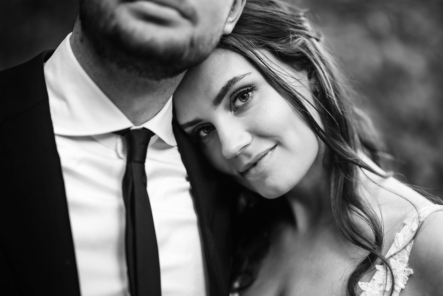 Close-up black and white wedding portrait of happy newlywed couple in a romantic embrace.