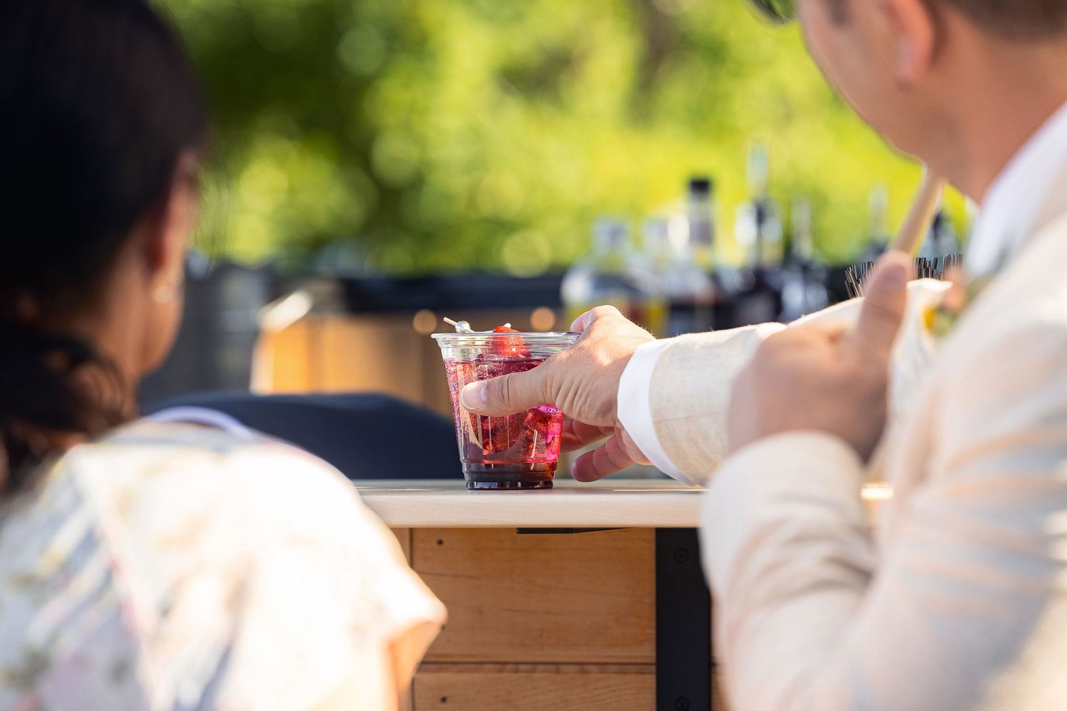 Close-up of hands preparing cocktails at an outdoor bar.