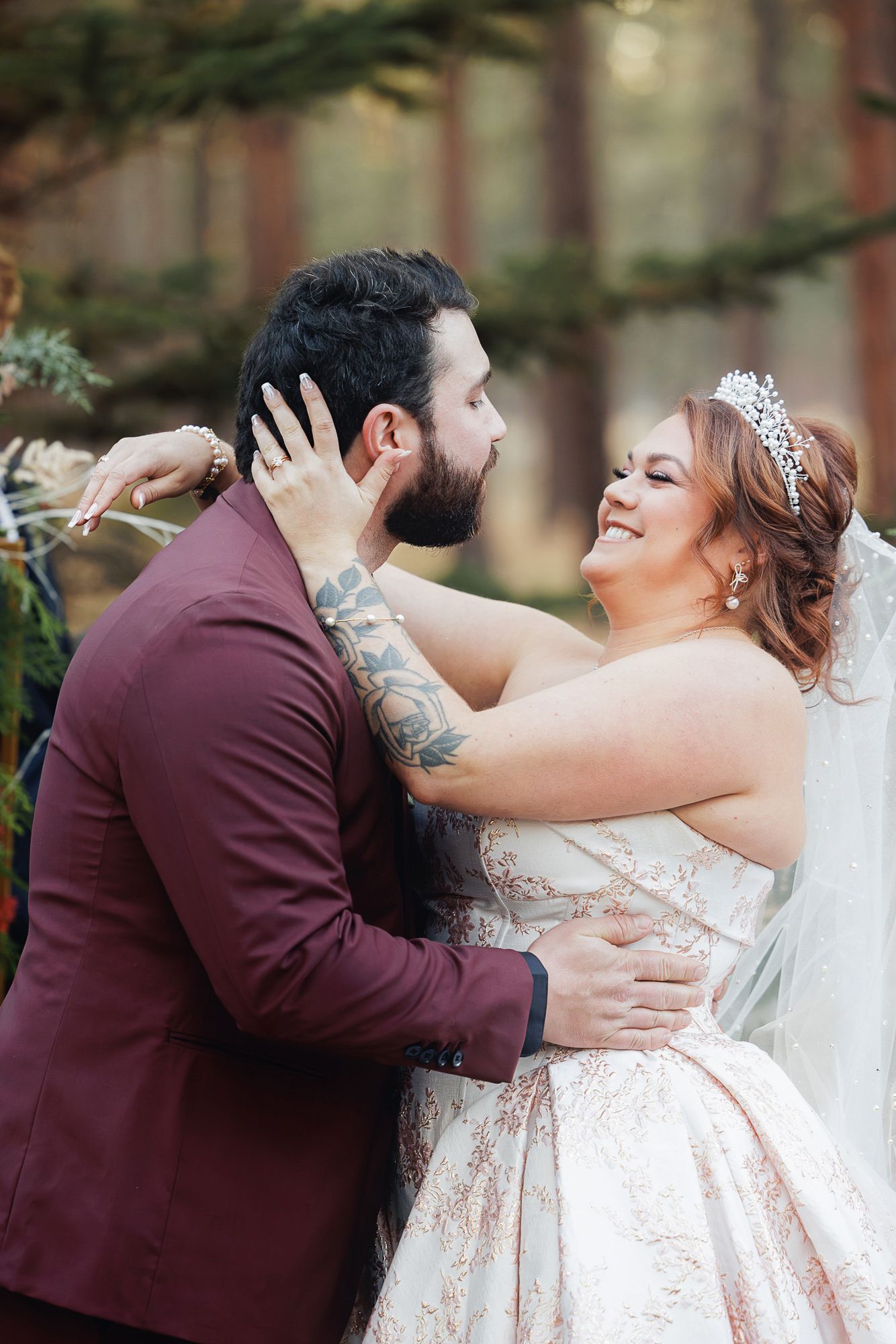Wedding couple shares intimate moments under evergreen trees during their forest ceremony.