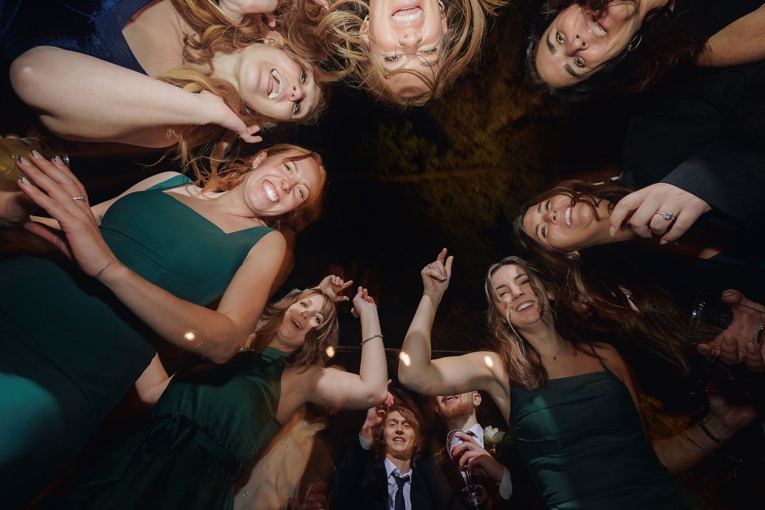 A creative overhead portrait of a group in dark clothing laying in a circular formation on the ground.