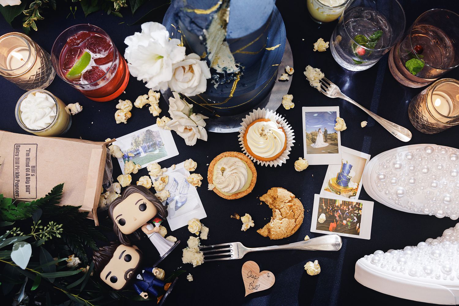 A collection of latte art coffee drinks arranged on a dark surface with scattered photos and decorative hearts.