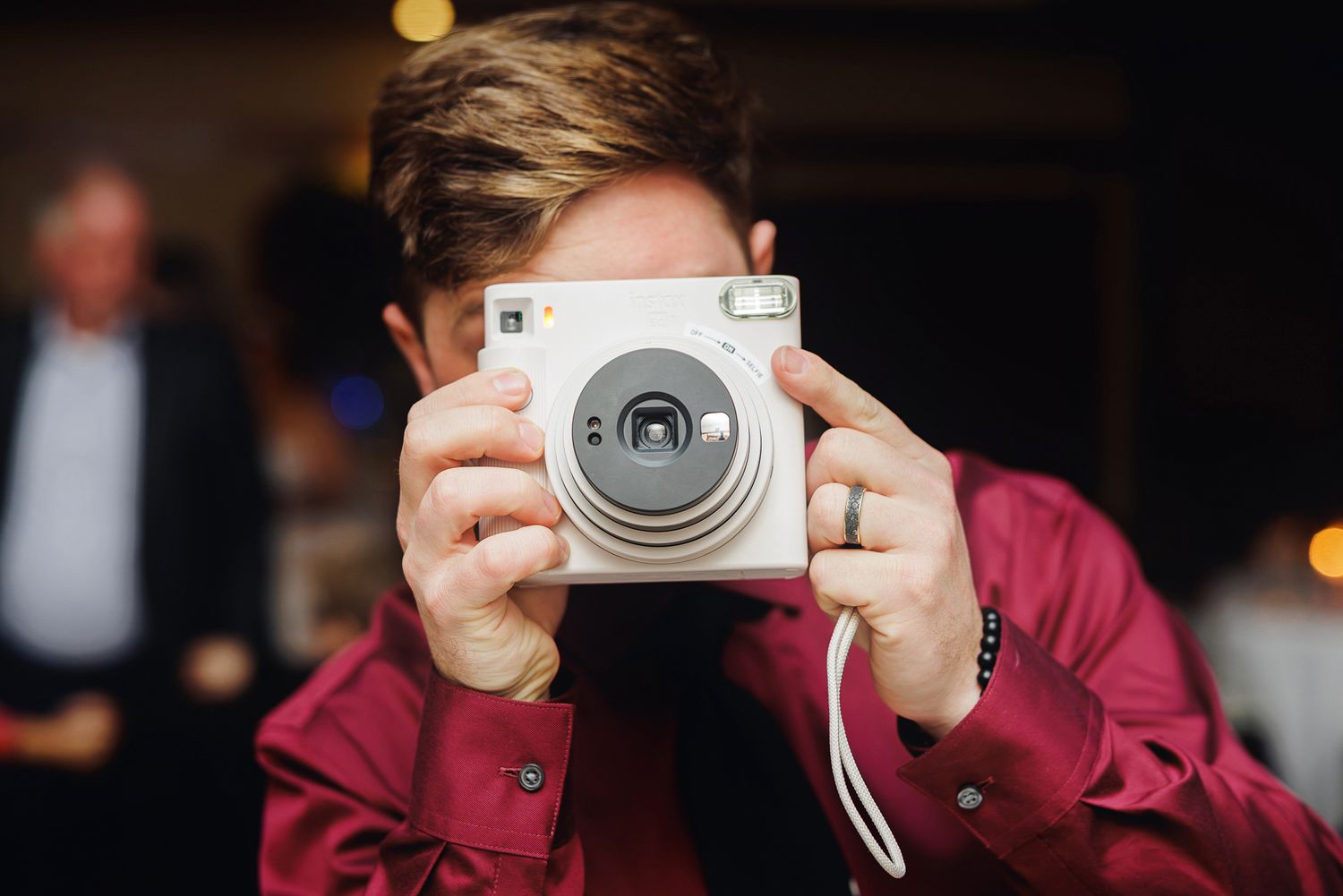 A sequence of hands holding a compact camera at different angles with blurred background lighting.