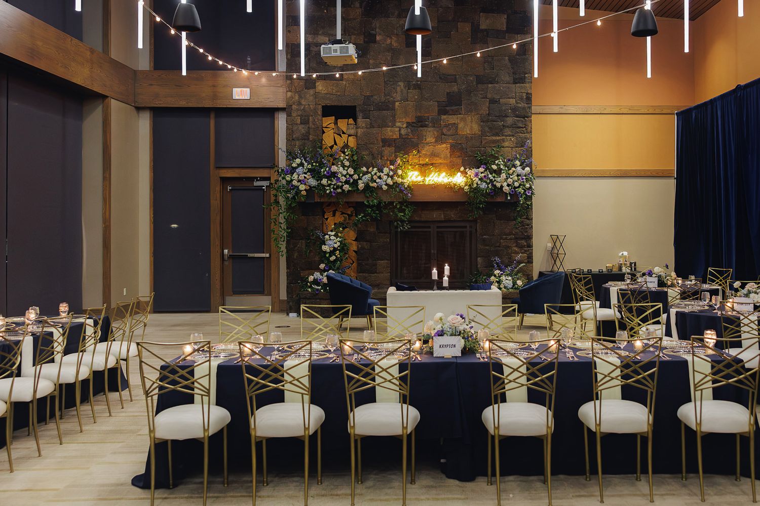 Modern event venue interior with hanging lights and long dining tables set up for a formal gathering.