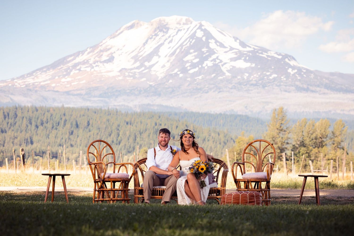 A couple sits in rustic wicker chairs with a magnificent snow-capped Mount Rainier rising in the background during sunset.