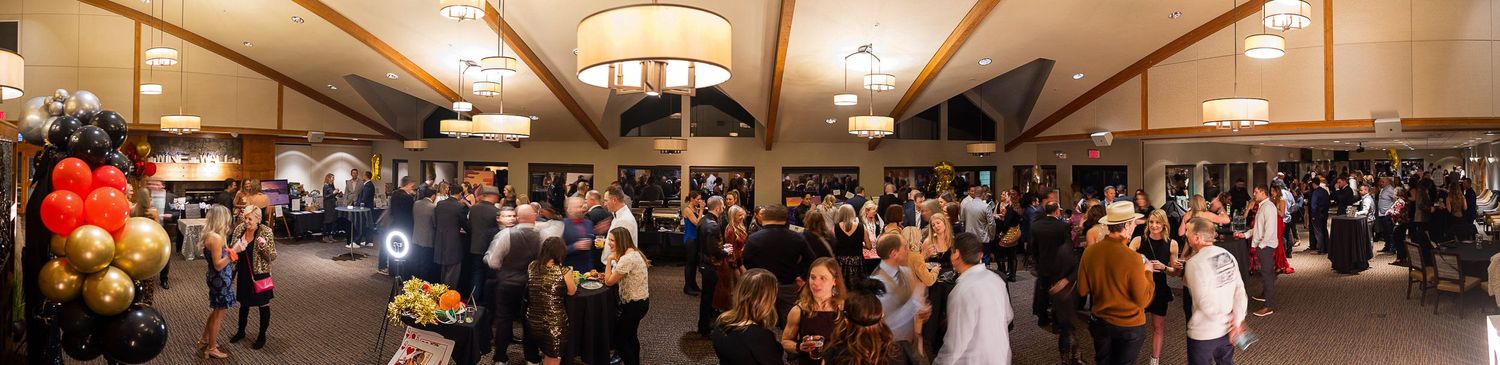 Panoramic view of a large banquet hall filled with guests at formal tables.