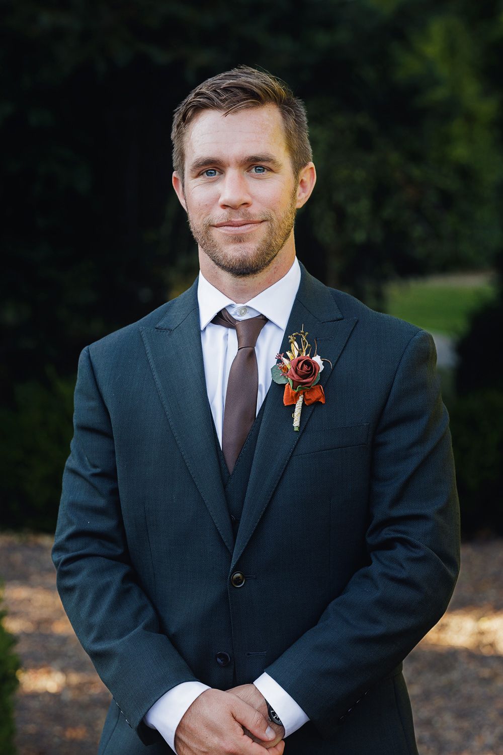 A groomsman in a dark suit with brown tie poses outdoors in a series of wedding photos.