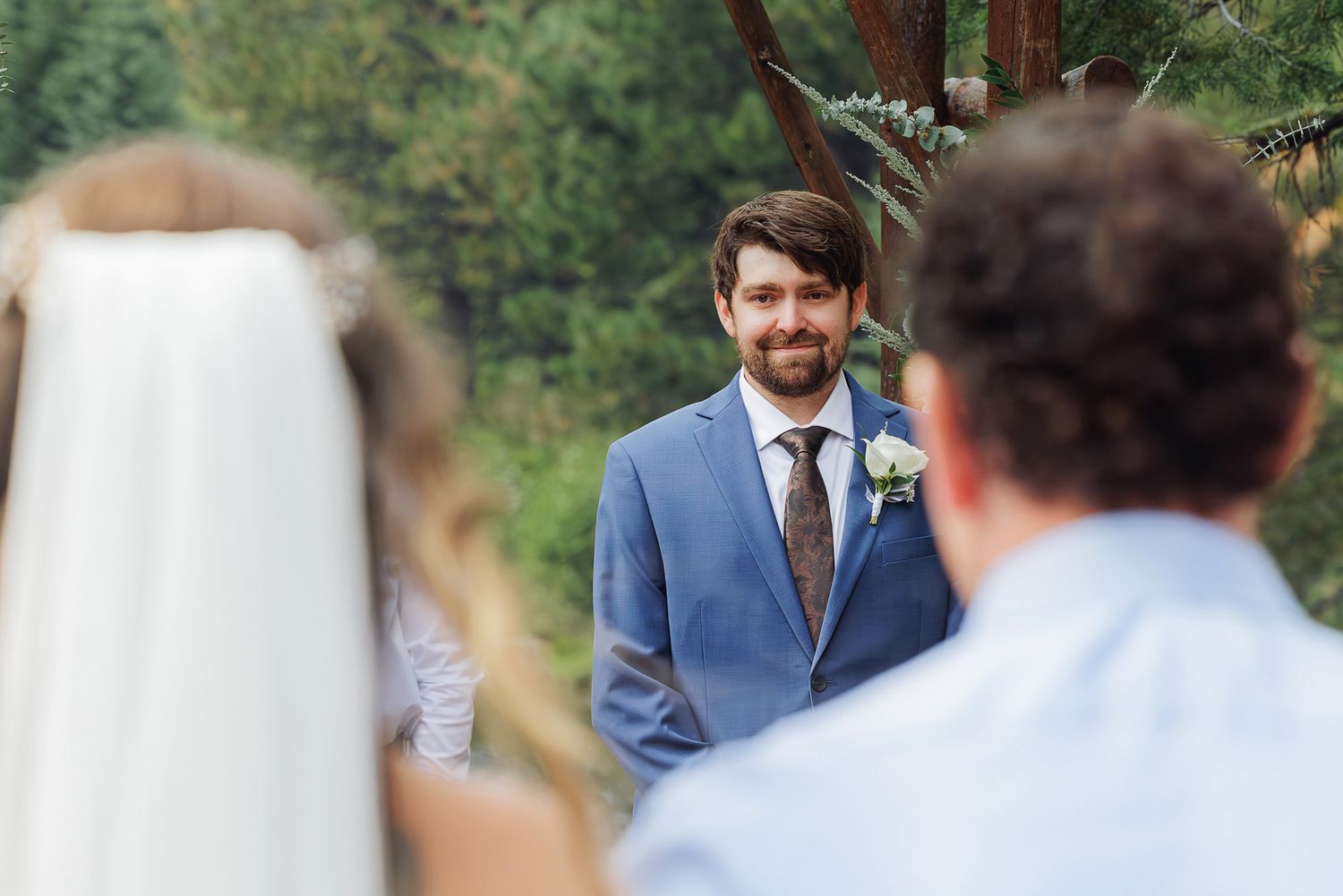 A group of wedding guests gather outdoors in a garden setting during a celebration.