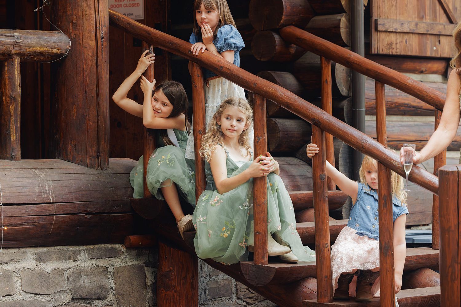 Children play on a rustic wooden staircase in a playful and energetic manner during a summer day.