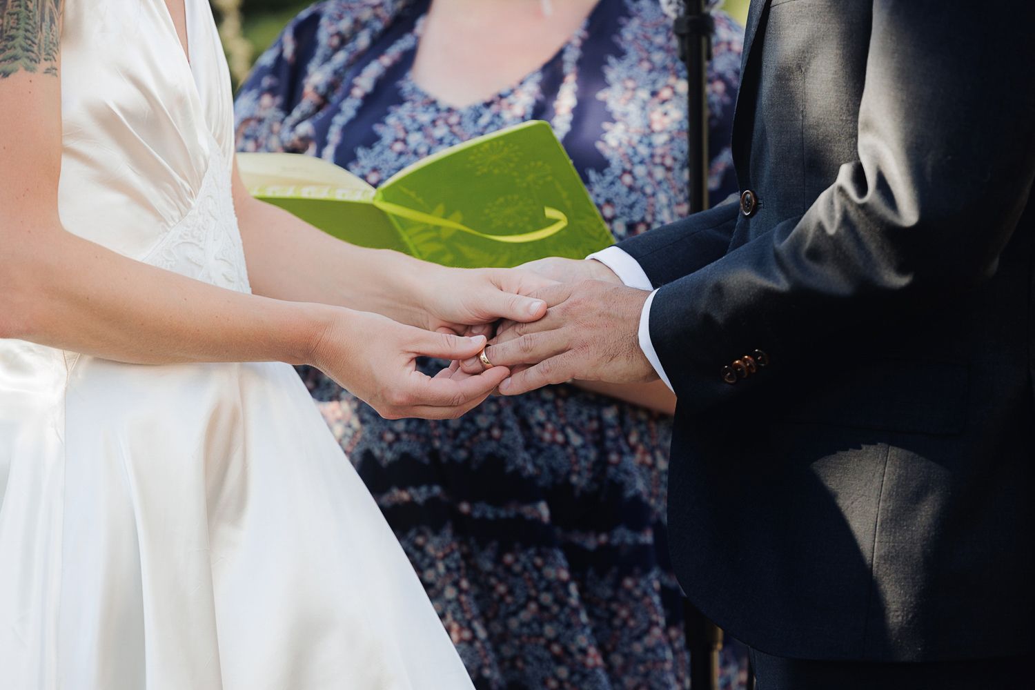 Close-up of hands holding a green leaf during an outdoor wedding ceremony.