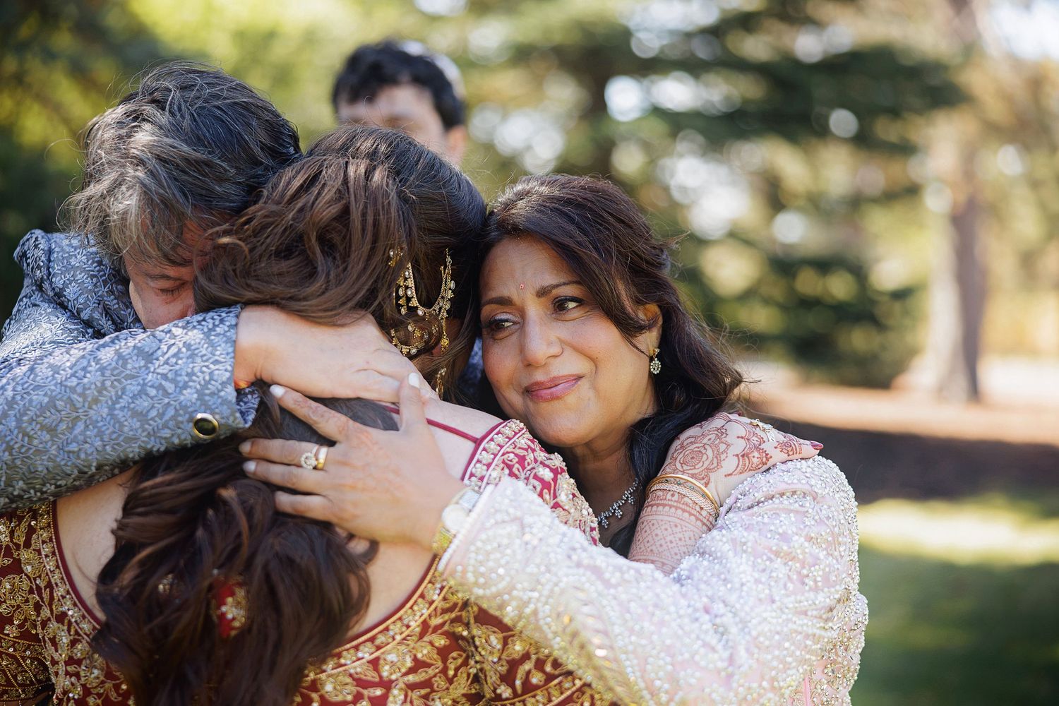 Women in traditional attire sharing a warm group hug outdoors at a garden celebration.