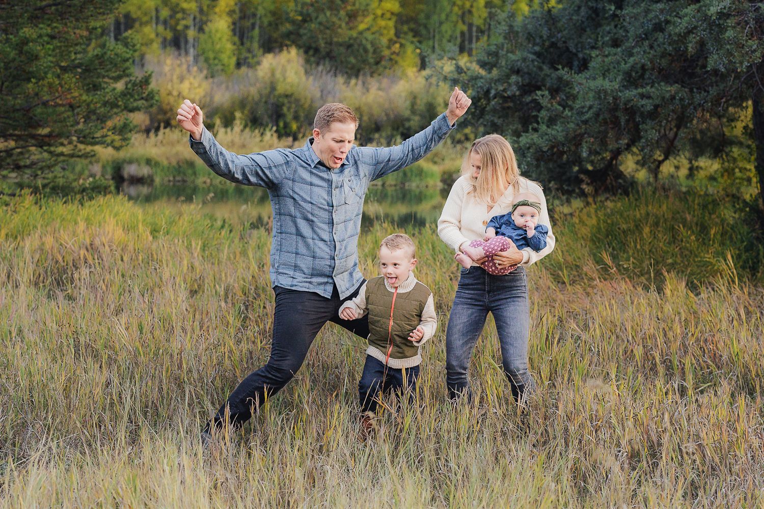 People enjoying a playful moment together in a grassy meadow surrounded by autumn trees and foliage.