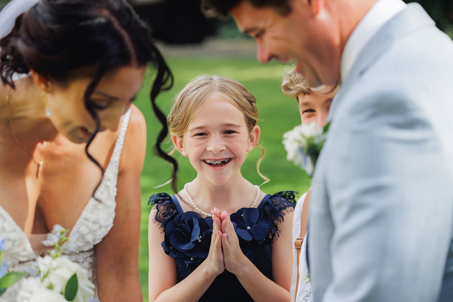 A group of wedding guests react with joy and excitement during an outdoor celebration.