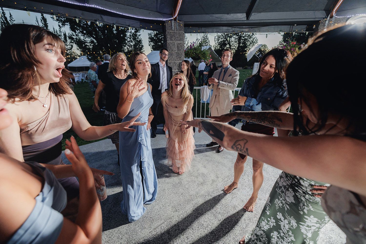 Group of people dancing and celebrating outdoors during a party on a sunny day.