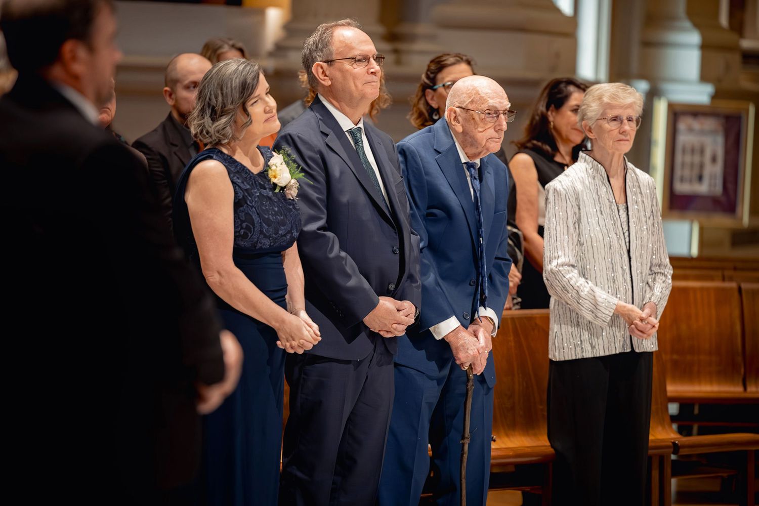 A group of well-dressed people stand in a row at a formal church service or ceremony.