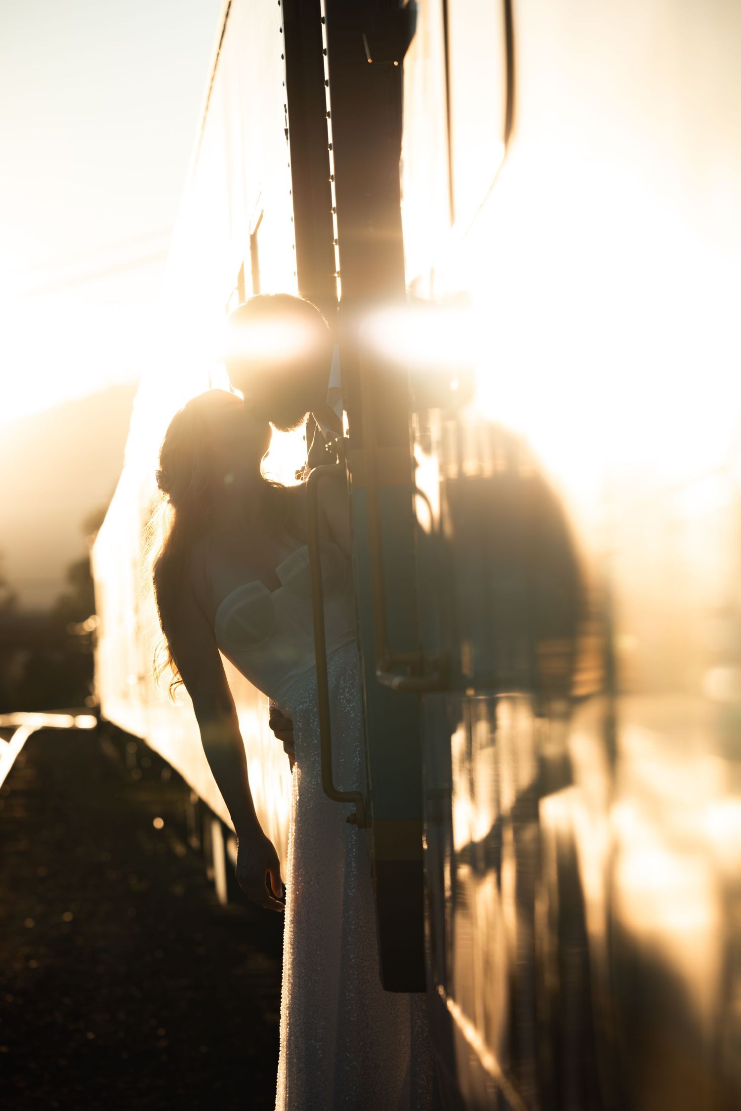 Silhouette of a bottle in front of sunlit urban scenery featuring dramatic sunlight and shadows.