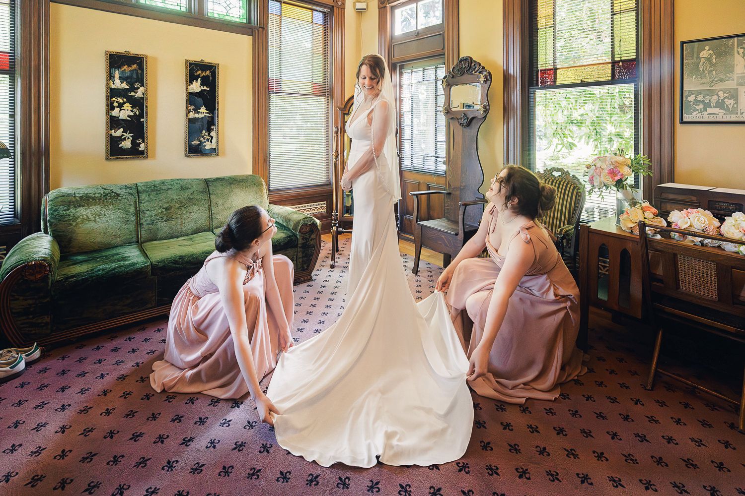 Elegant wedding preparation scene in a vintage room with brides and bridesmaids in soft pink dresses.