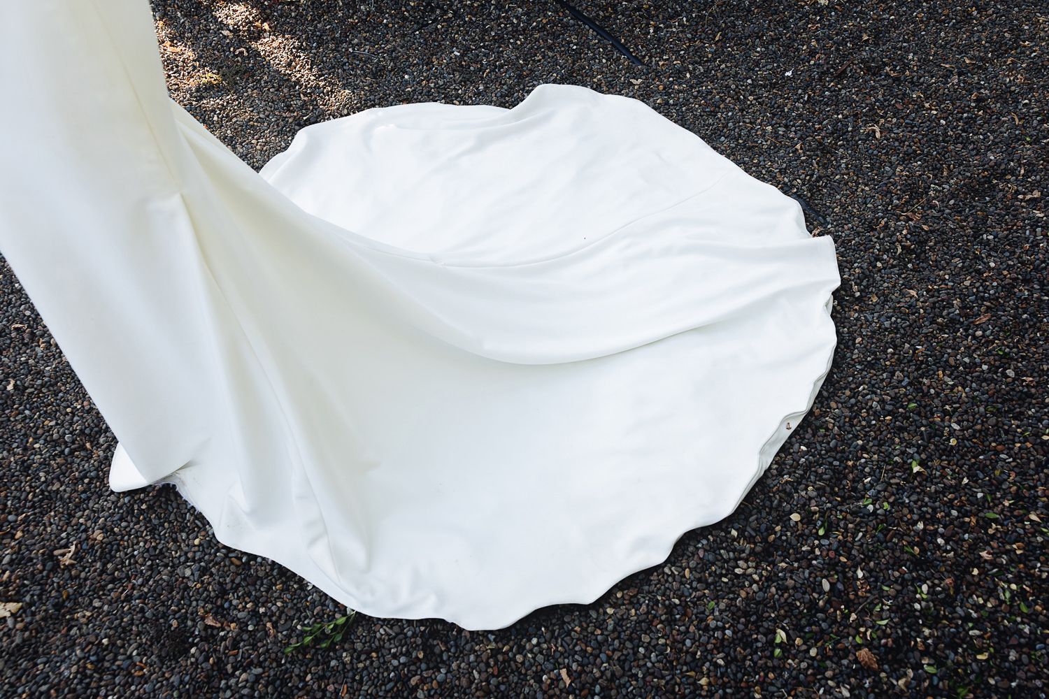 A flowing white fabric ripples and twists against a dark textured background creating an ethereal effect.