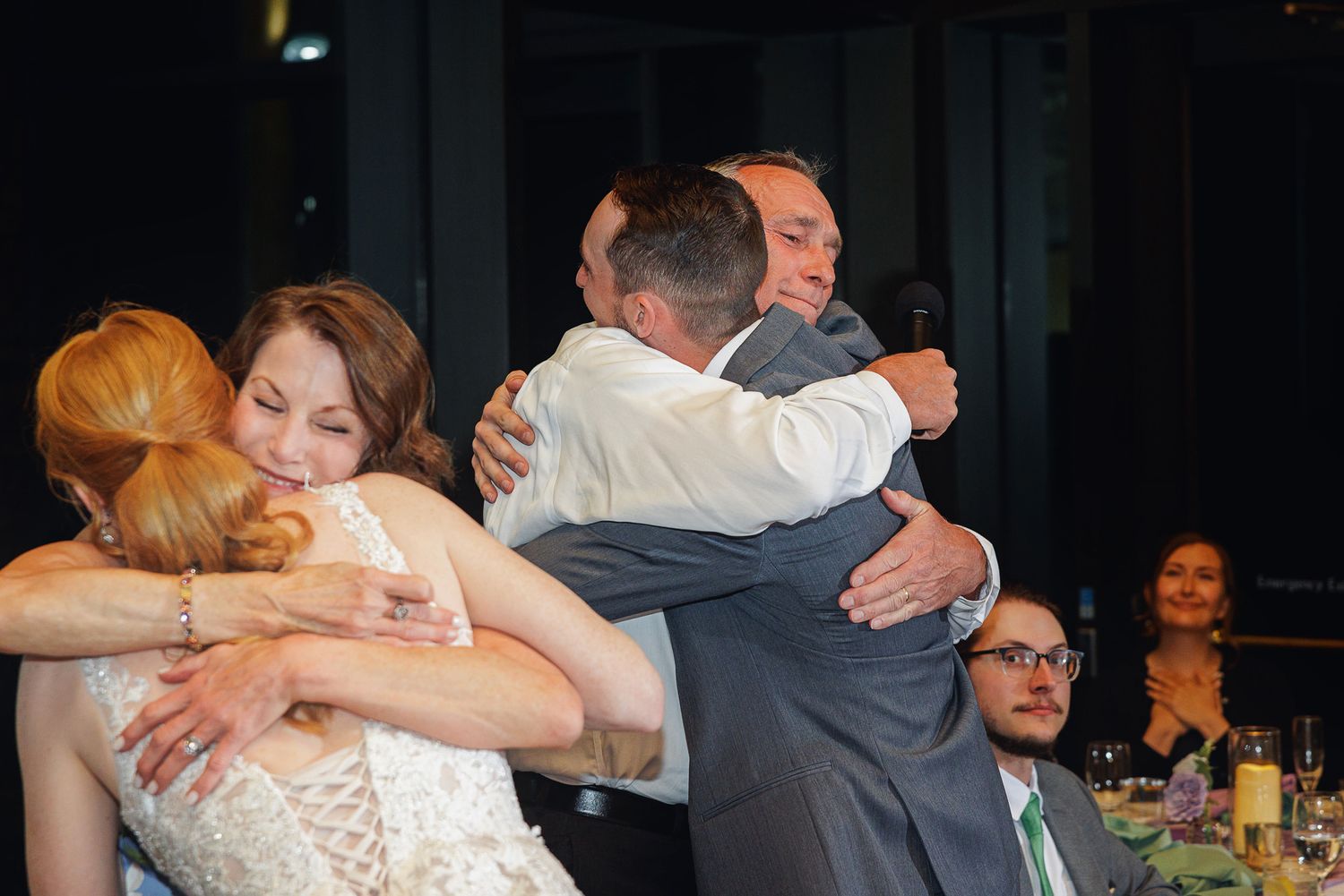 Wedding guests sharing warm embraces and hugs during a reception celebration indoors.