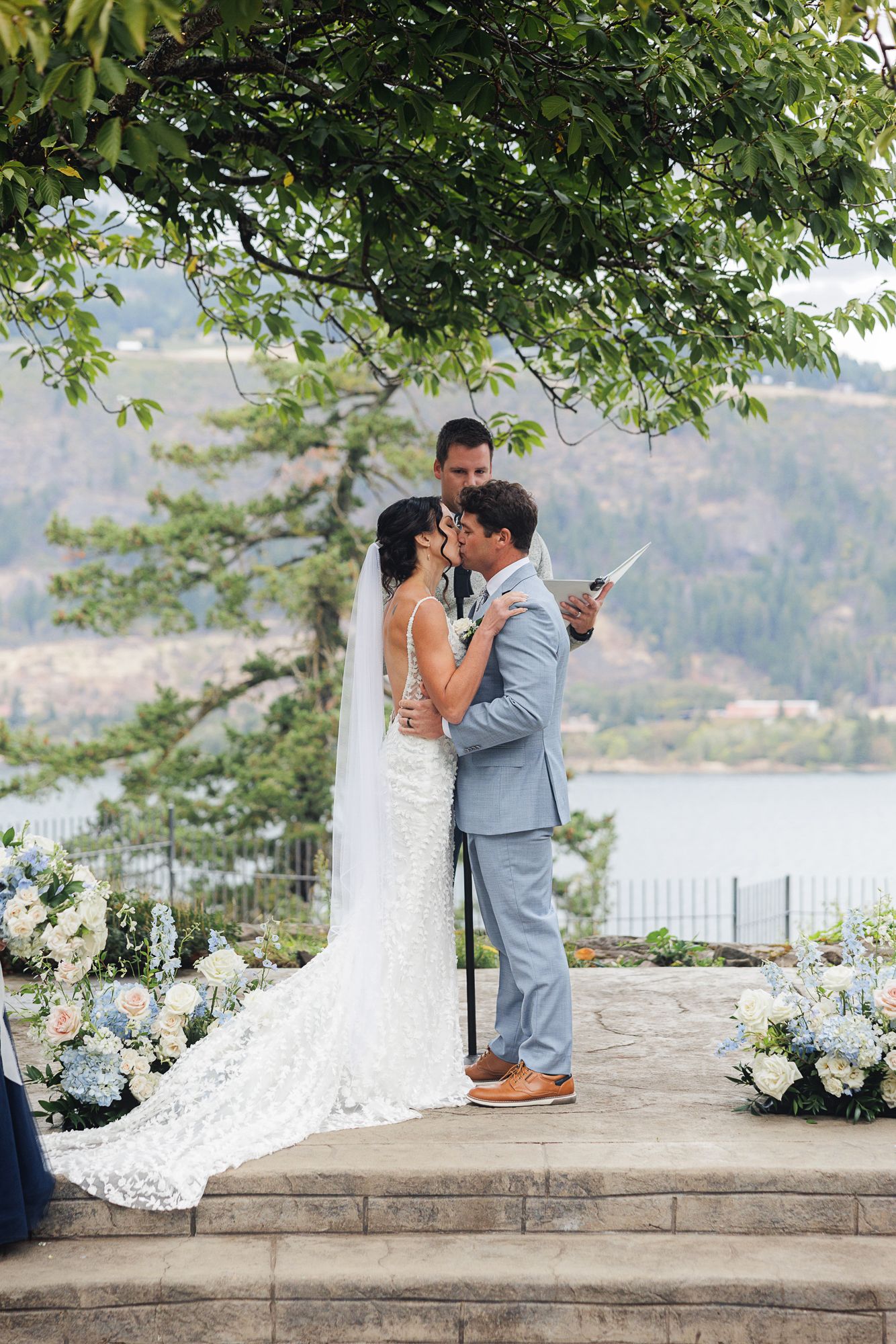 Couple shares intimate moments during their waterfront wedding ceremony with white floral decorations.