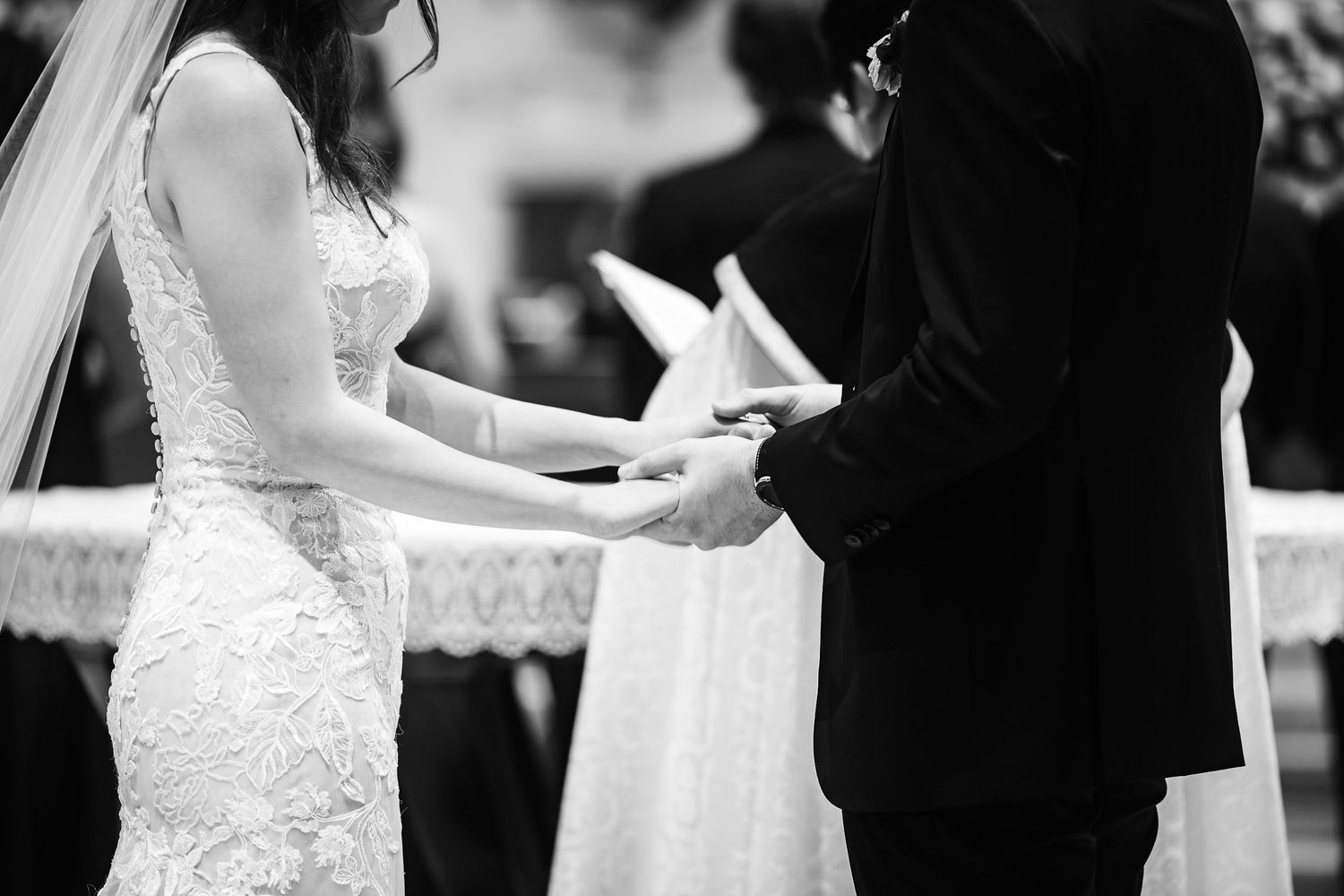 Black and white close-up shot of bride and groom exchanging vows during wedding ceremony.