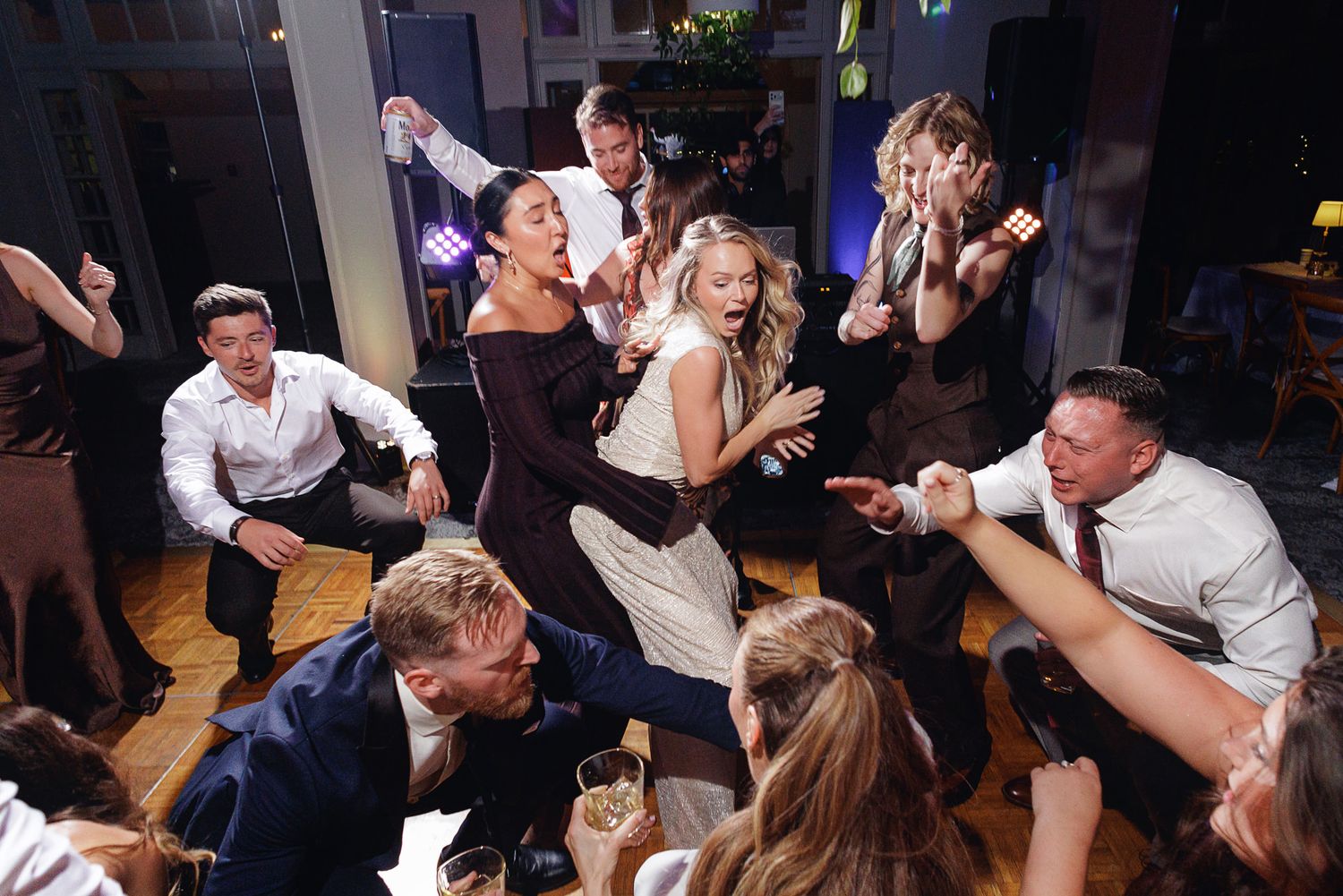 Joyful wedding reception guests dancing and celebrating together on the dance floor in a lively indoor venue.