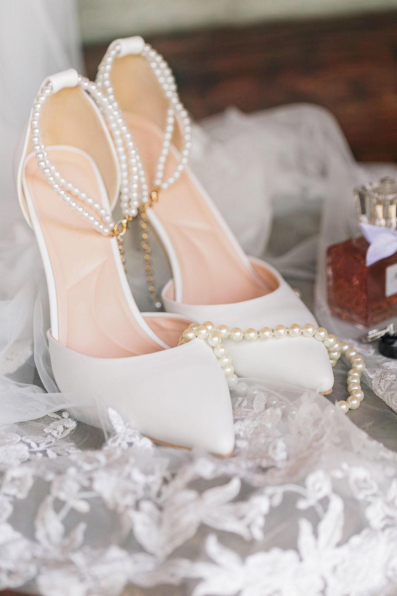 White bridal shoes displayed on a bed of crystal-like decorative stones create an elegant wedding detail shot.