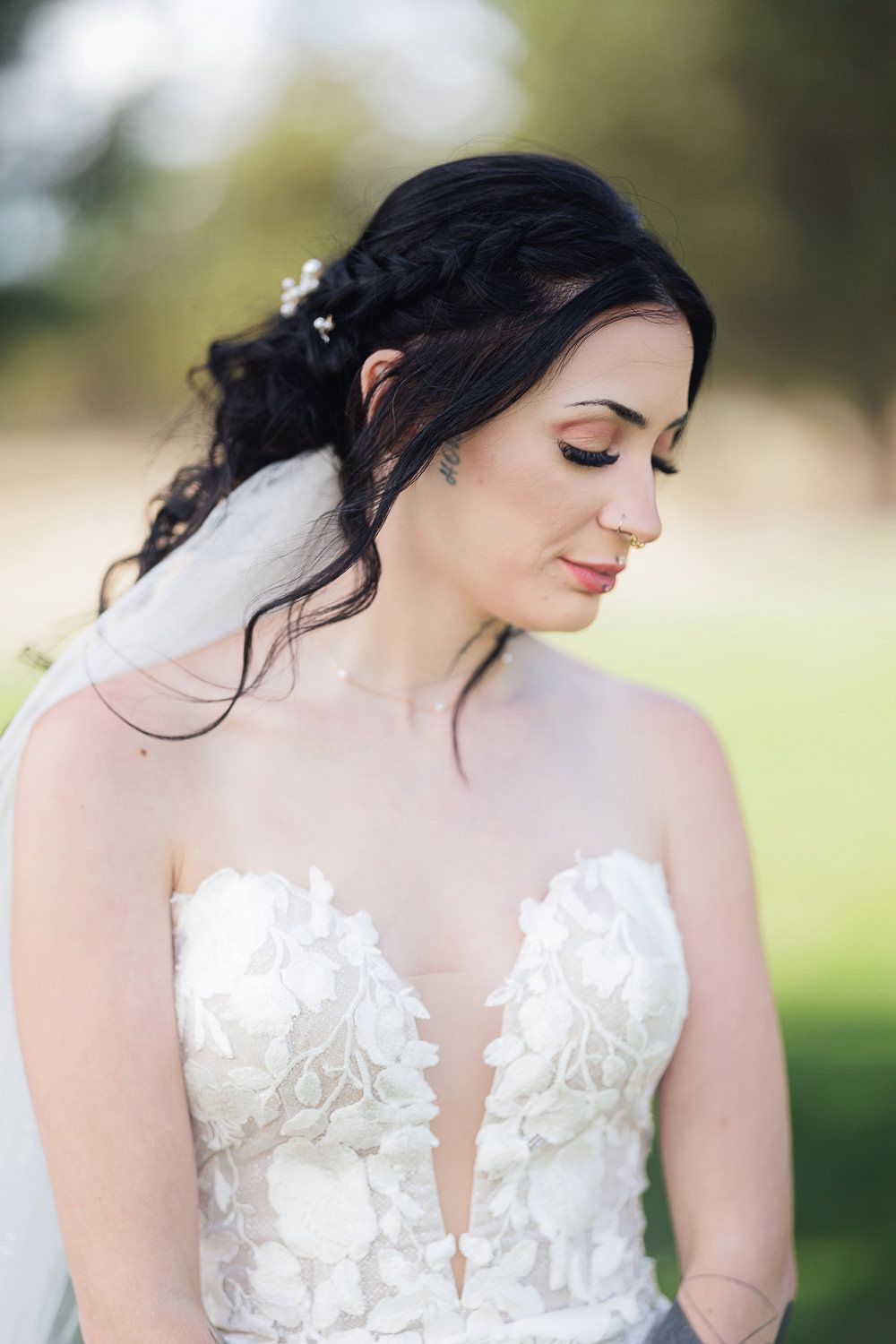 Bridal portraits showing delicate details of a white lace wedding dress with plunging neckline against soft outdoor lighting.