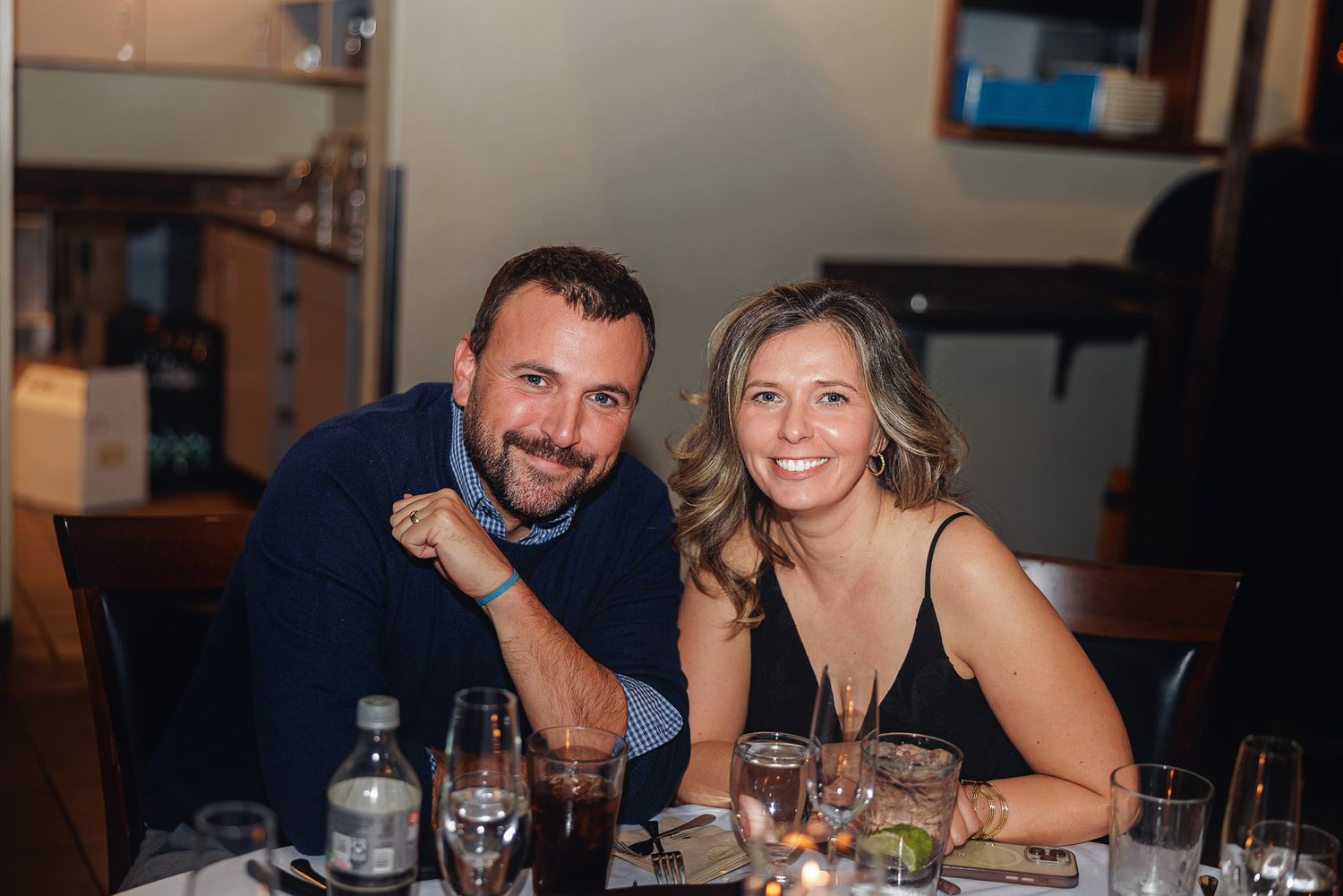 People enjoying dinner and drinks at a casual restaurant table in the evening.