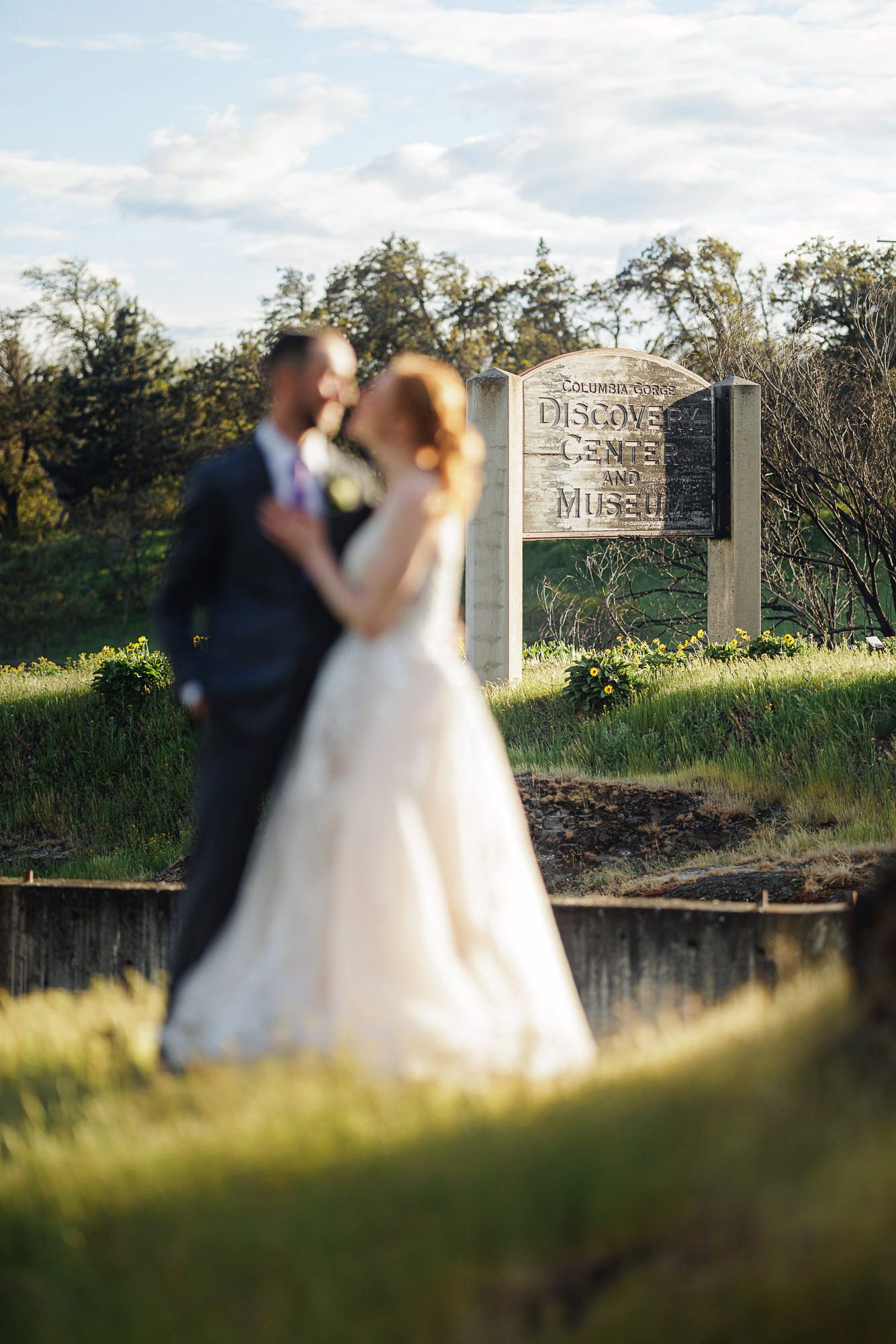 Bride and groom sharing a romantic moment near a Discovery Center and Museum sign outdoors on their wedding day.