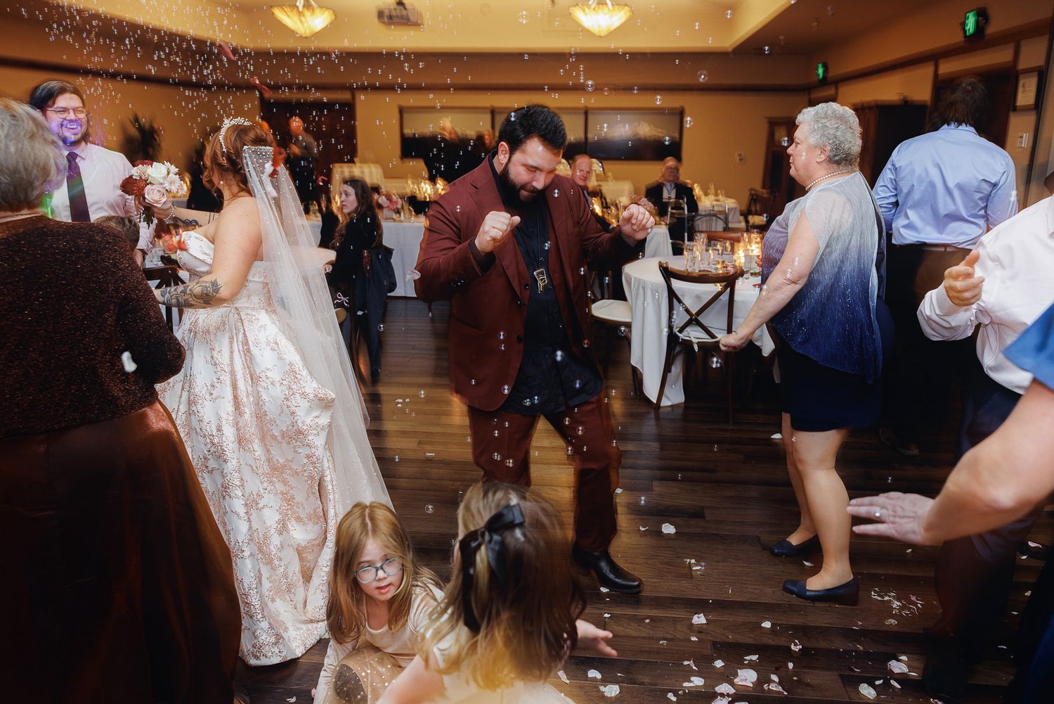 Wedding reception dance floor filled with guests celebrating as confetti falls through the air.
