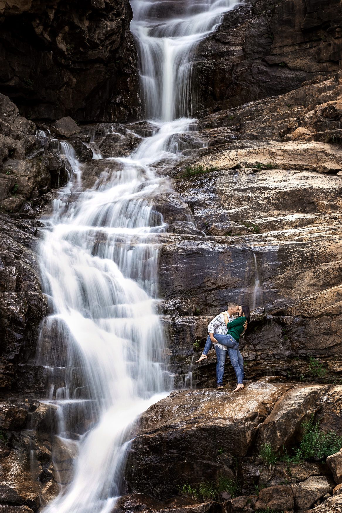 Multiple views of a cascading waterfall flowing down dark rocky cliffs in a forest setting.