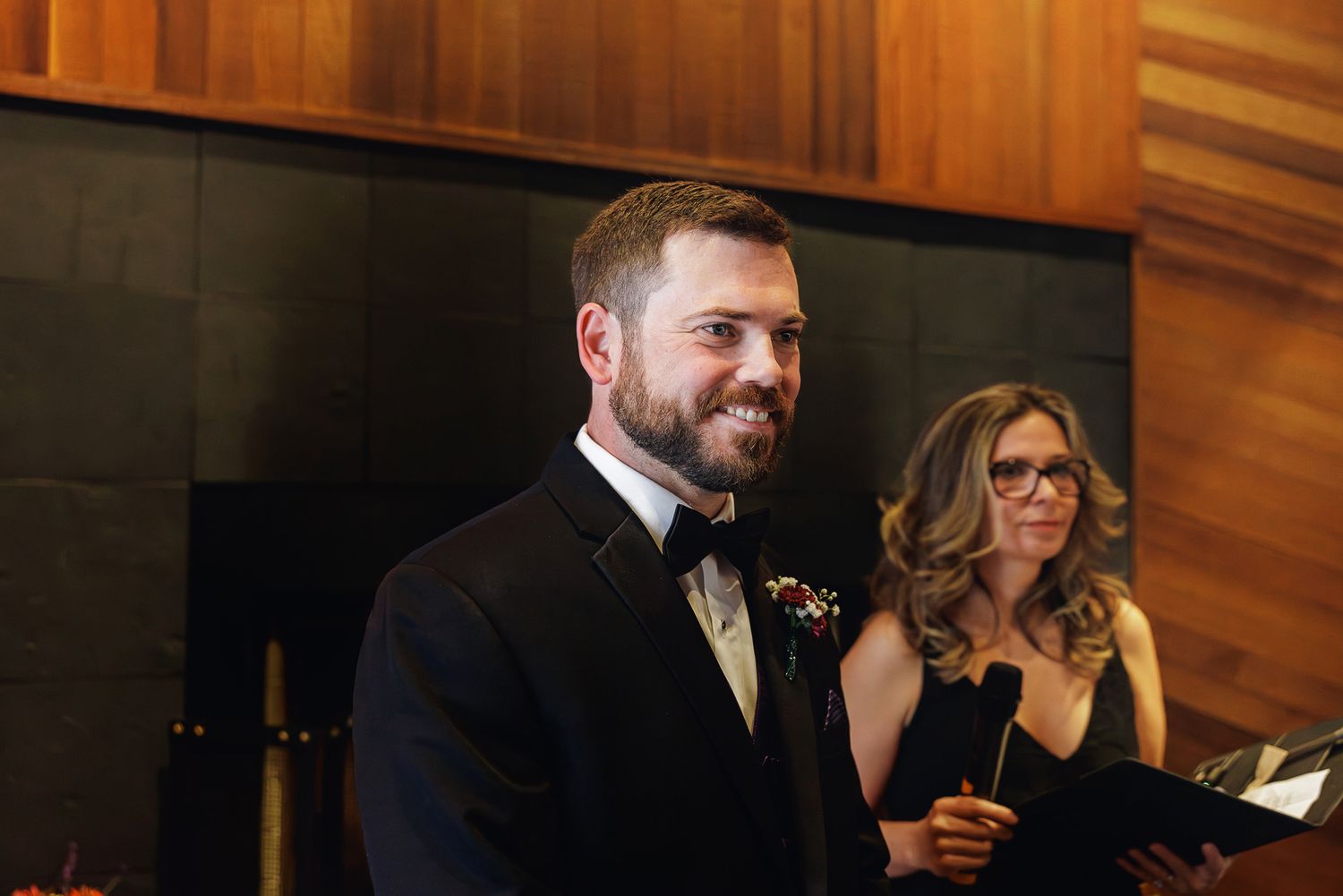 A couple shares a joyful moment while looking at their phones during an elegant indoor event.
