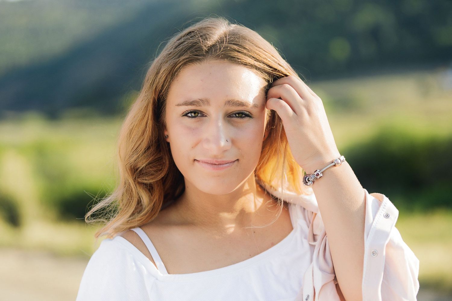 Summer portrait of person in white top with sunlit glow in outdoor setting.
