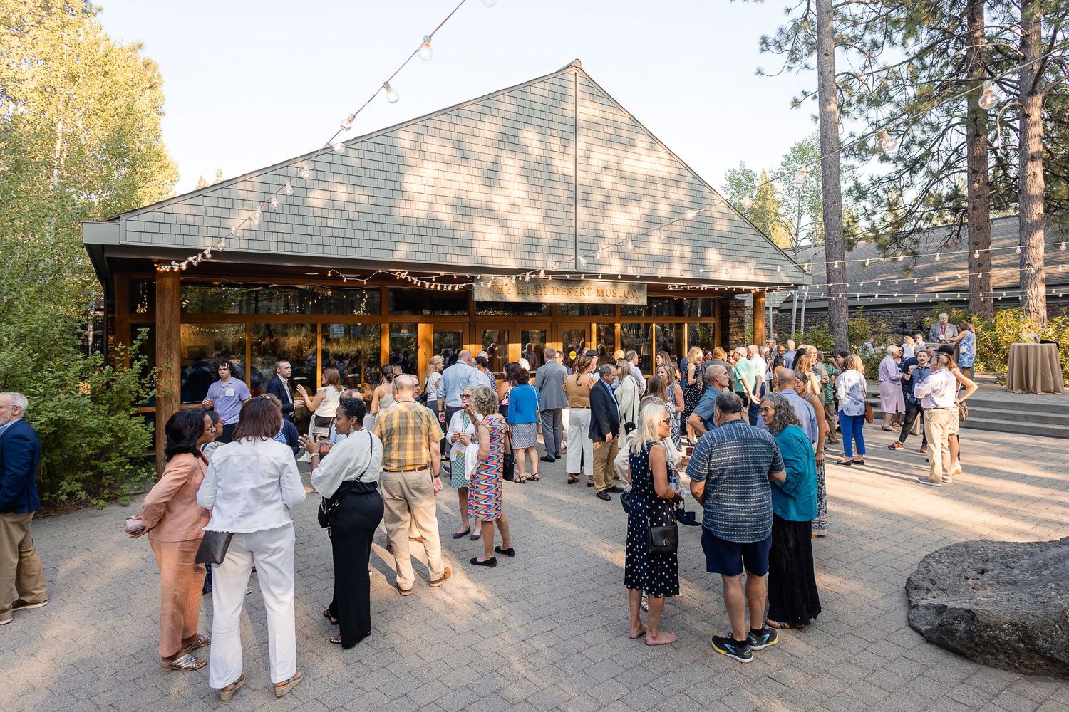Crowd gathered outside rustic lodge building during evening event.