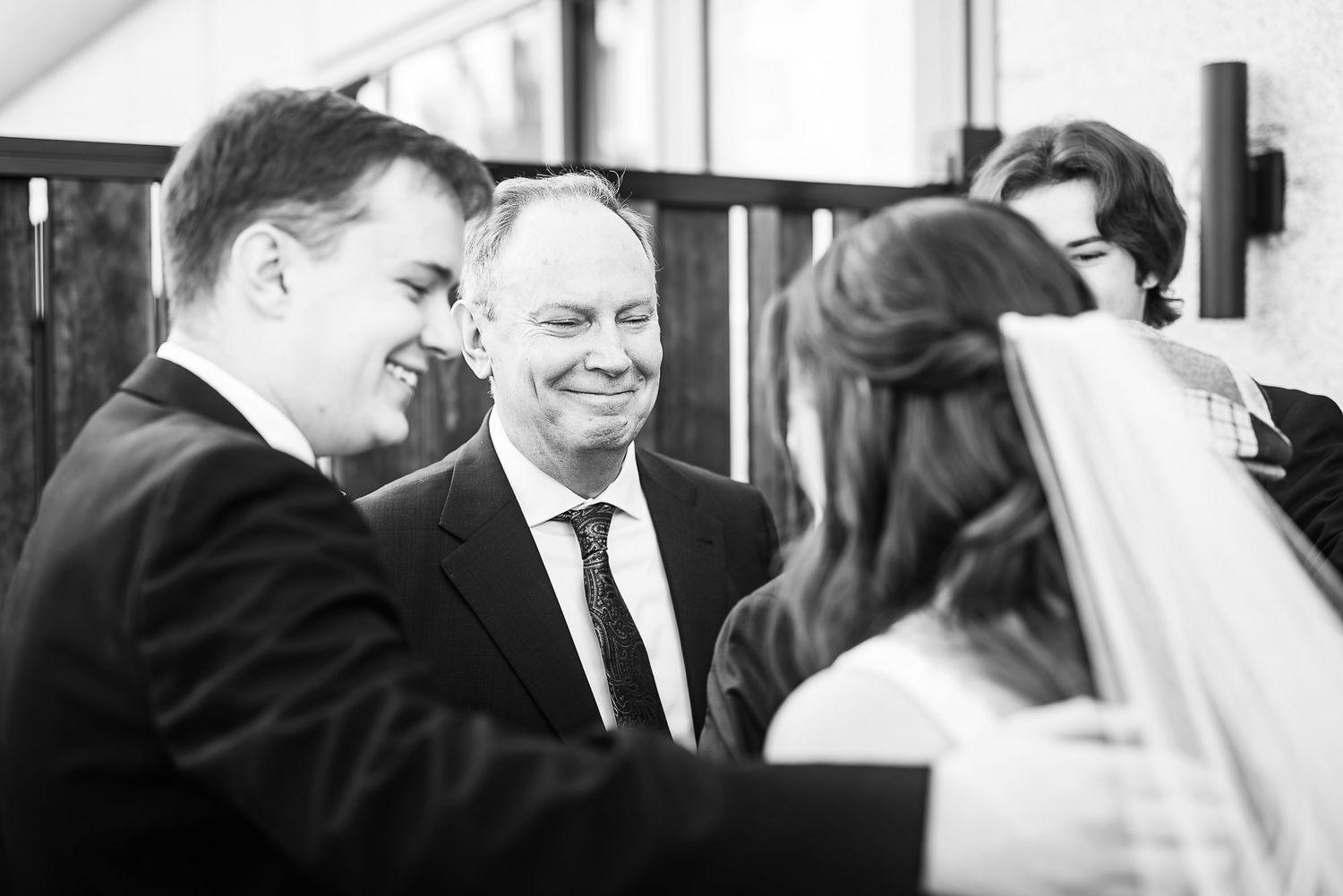 A candid black and white moment of joy and laughter shared during a wedding ceremony.