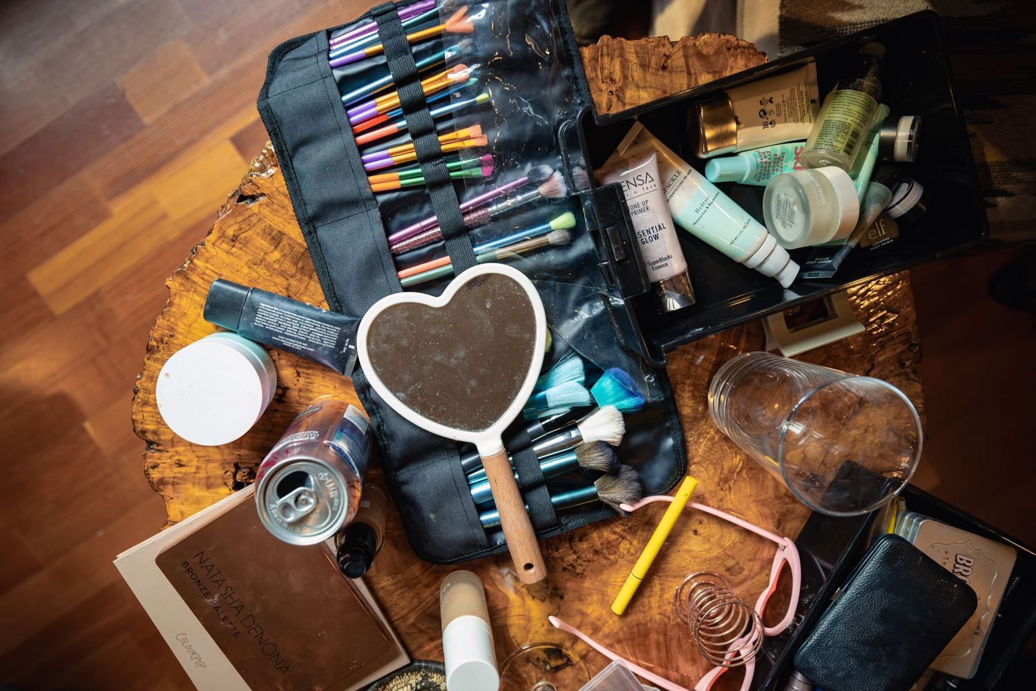 Artistic supplies including markers in a black case, drinks in mason jars, and crafting materials arranged on wooden surface.