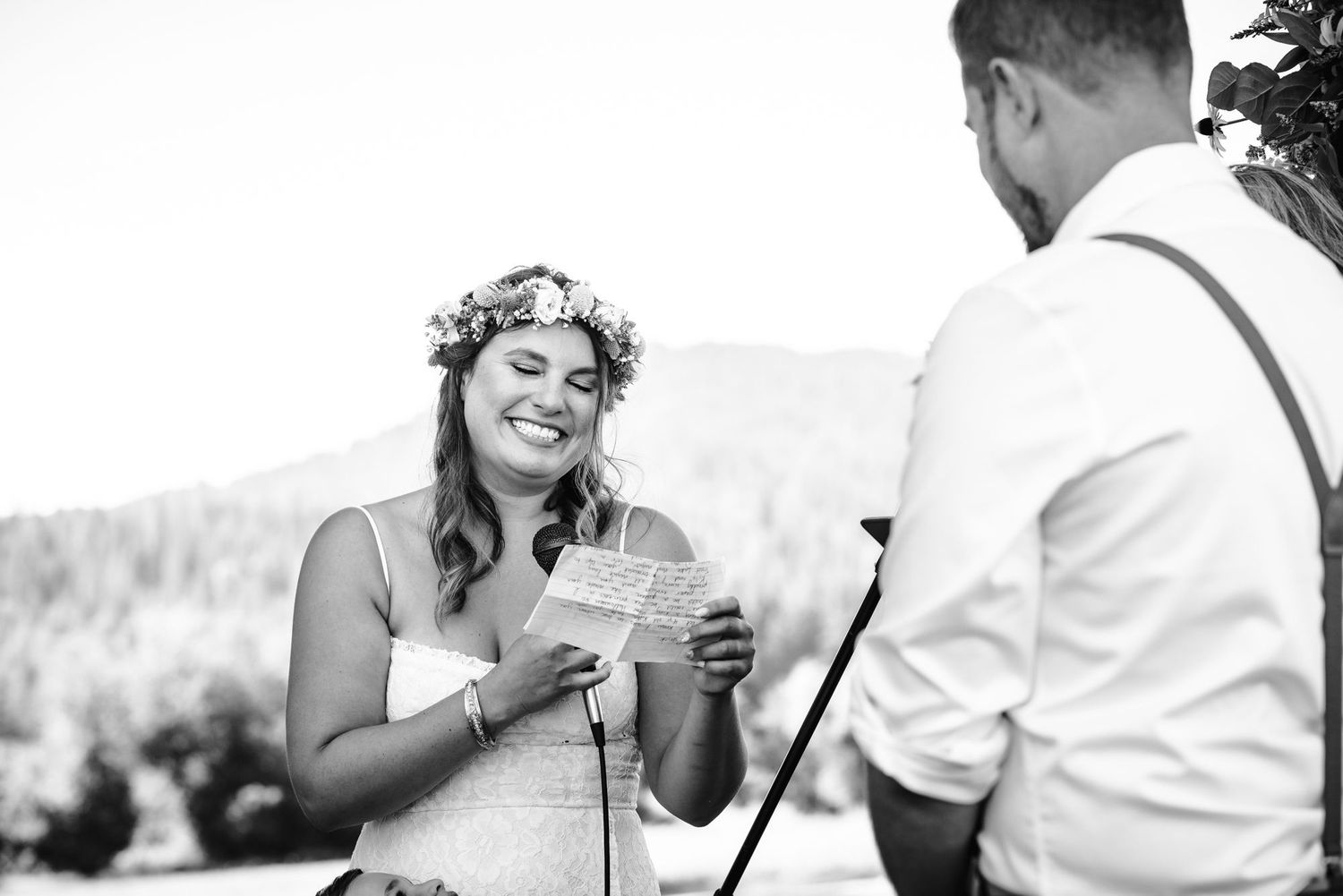 A couple sharing joyful moments during an outdoor wedding ceremony with mountains in the background.