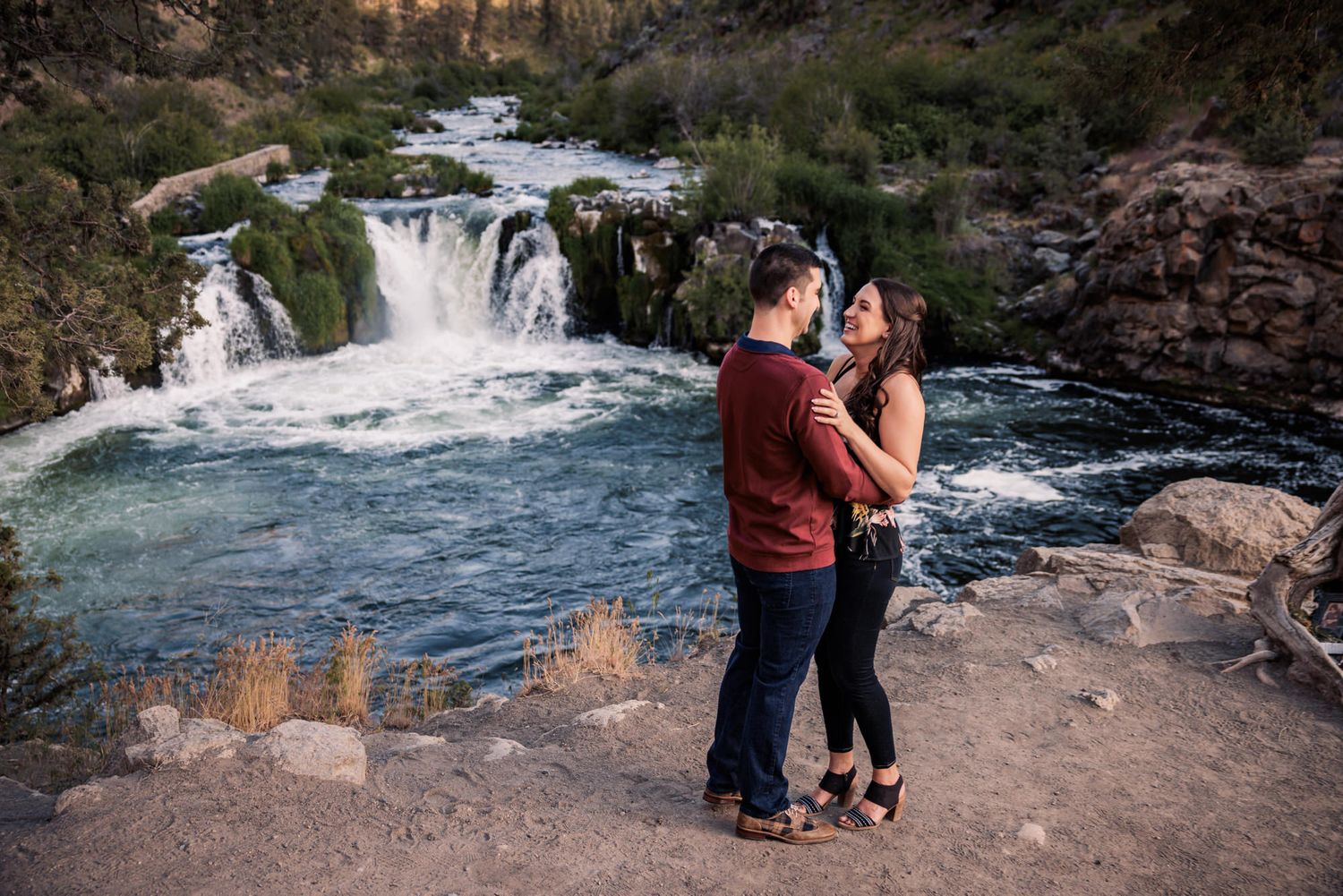 People enjoying scenic views of rushing waterfalls and rocky landscapes at a natural park destination.
