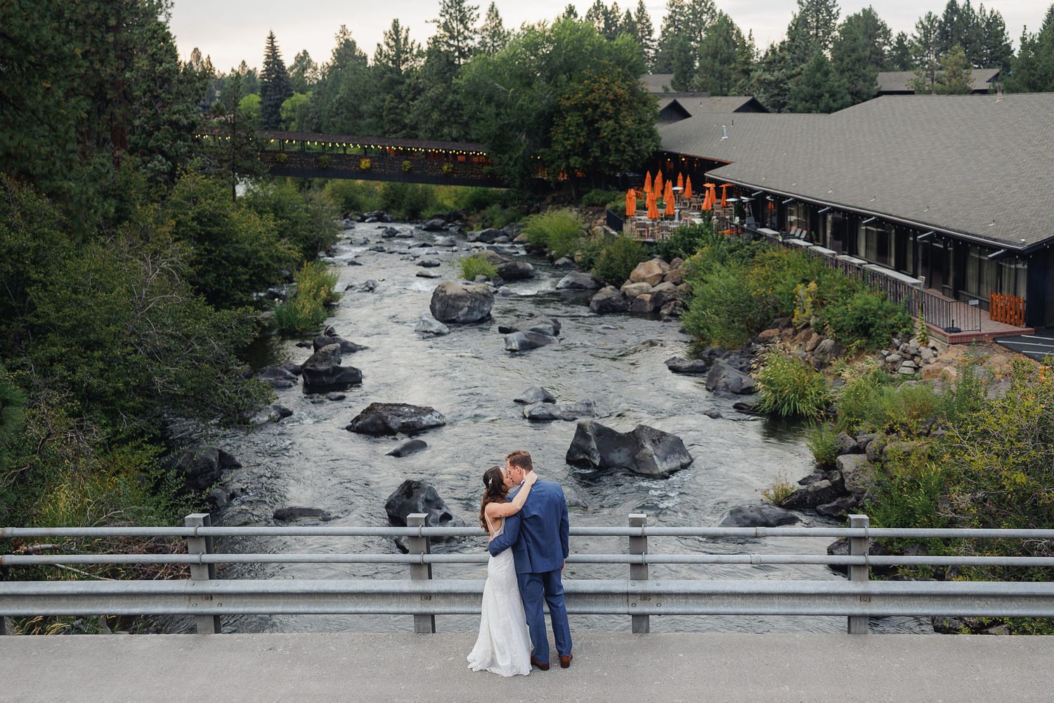 A scenic river flows through a wooded landscape with rustic buildings and bridges visible along its banks.