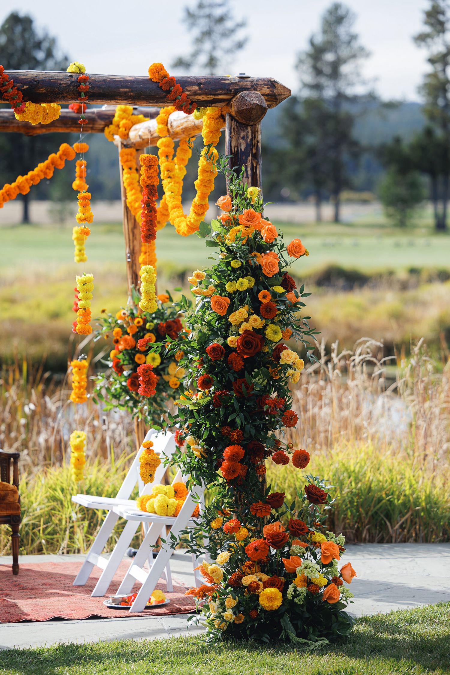 Vibrant marigold garland wedding mandap with orange and yellow floral arrangements outdoors.