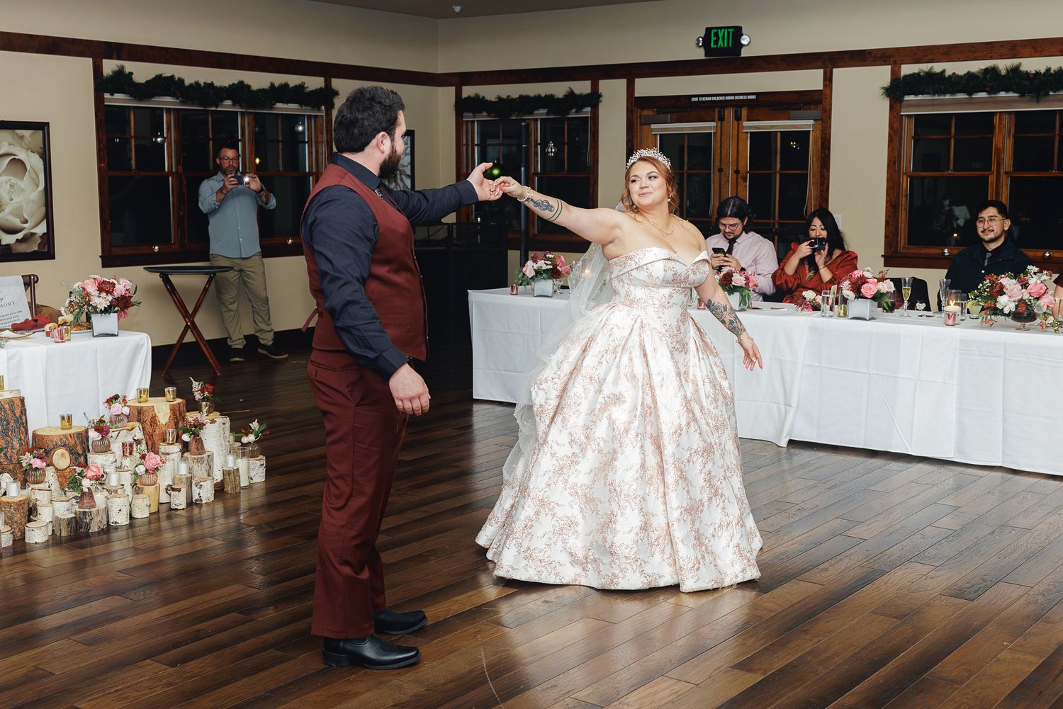 Couples dancing together on a wooden floor at an elegant ballroom event with tables and decorations visible.