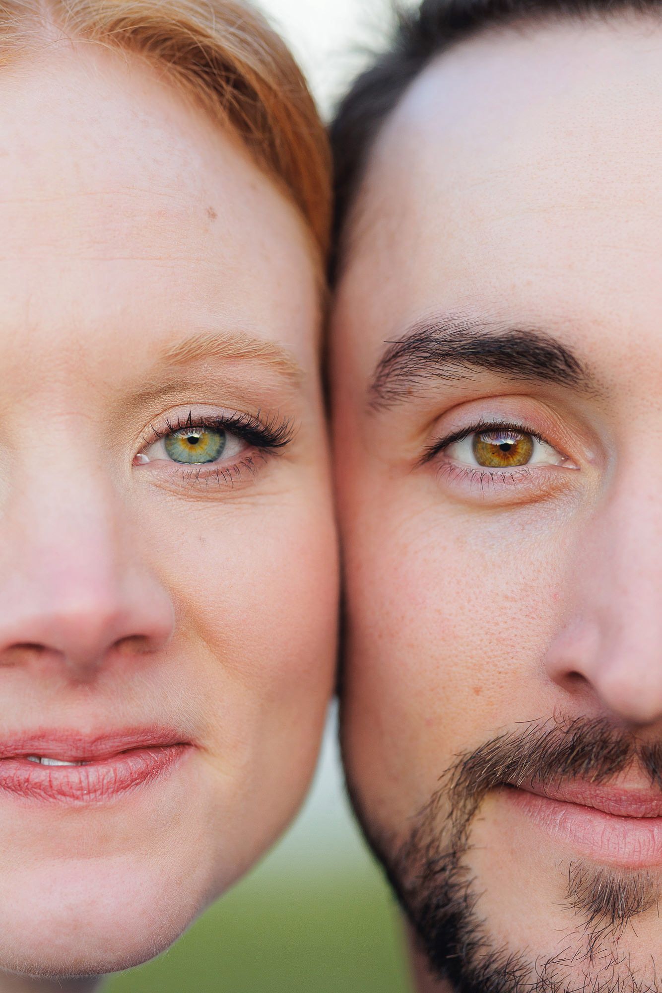 Close-up portrait of a man and woman with striking hazel-green eyes, red hair and dark beard, faces side by side.