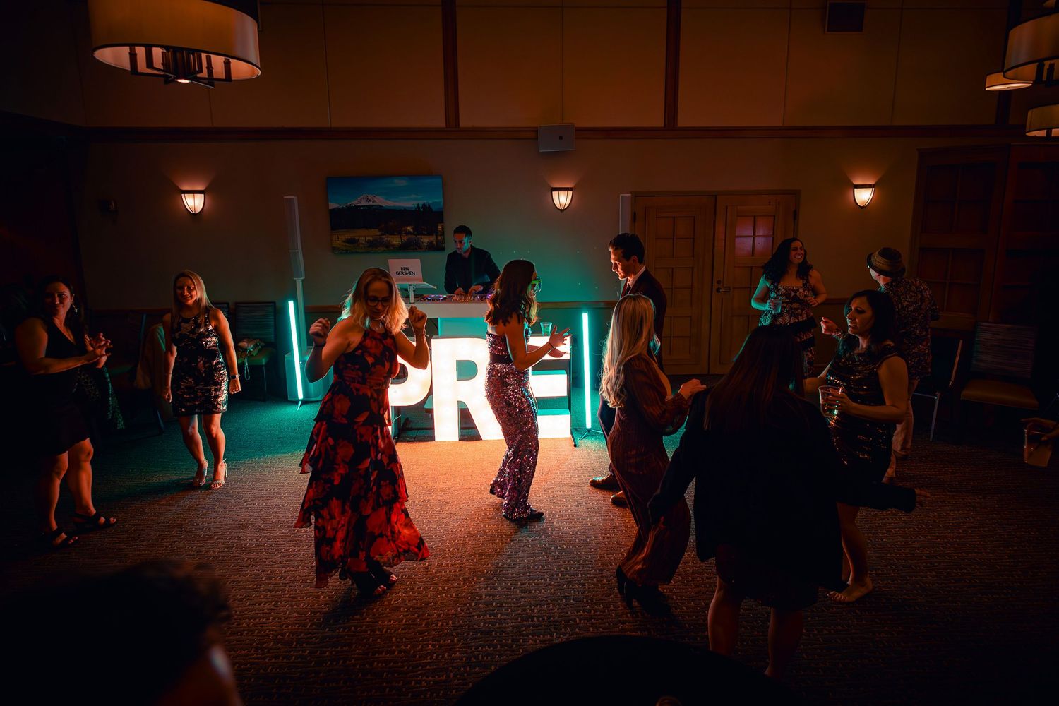 People dancing in a dimly lit room with neon lights creating an atmospheric party environment.