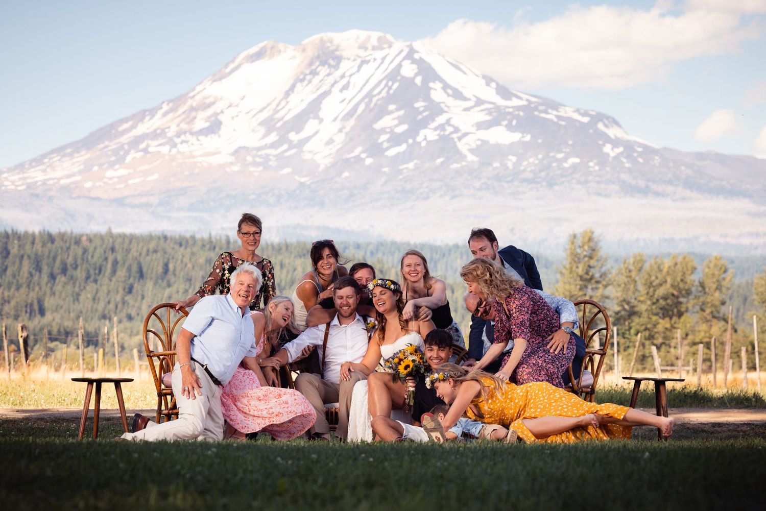 Wedding party gathered for a group photo with a majestic snow-capped mountain peak in the background.
