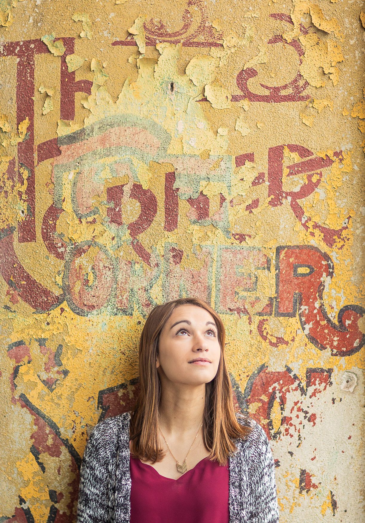 Person standing against weathered yellow wall with faded graffiti art.
